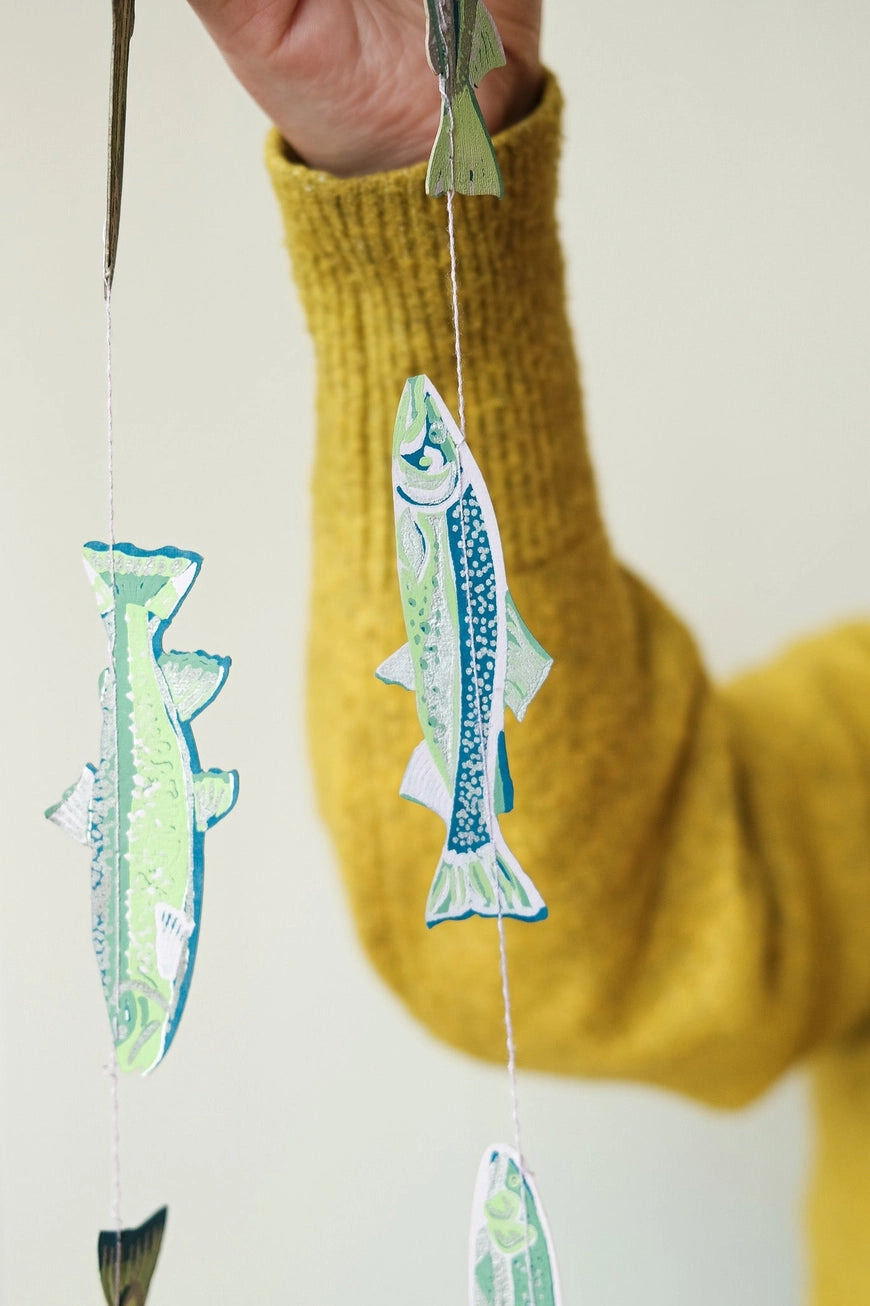 Hand holding a fish-shaped decoration with a yellow sweater background