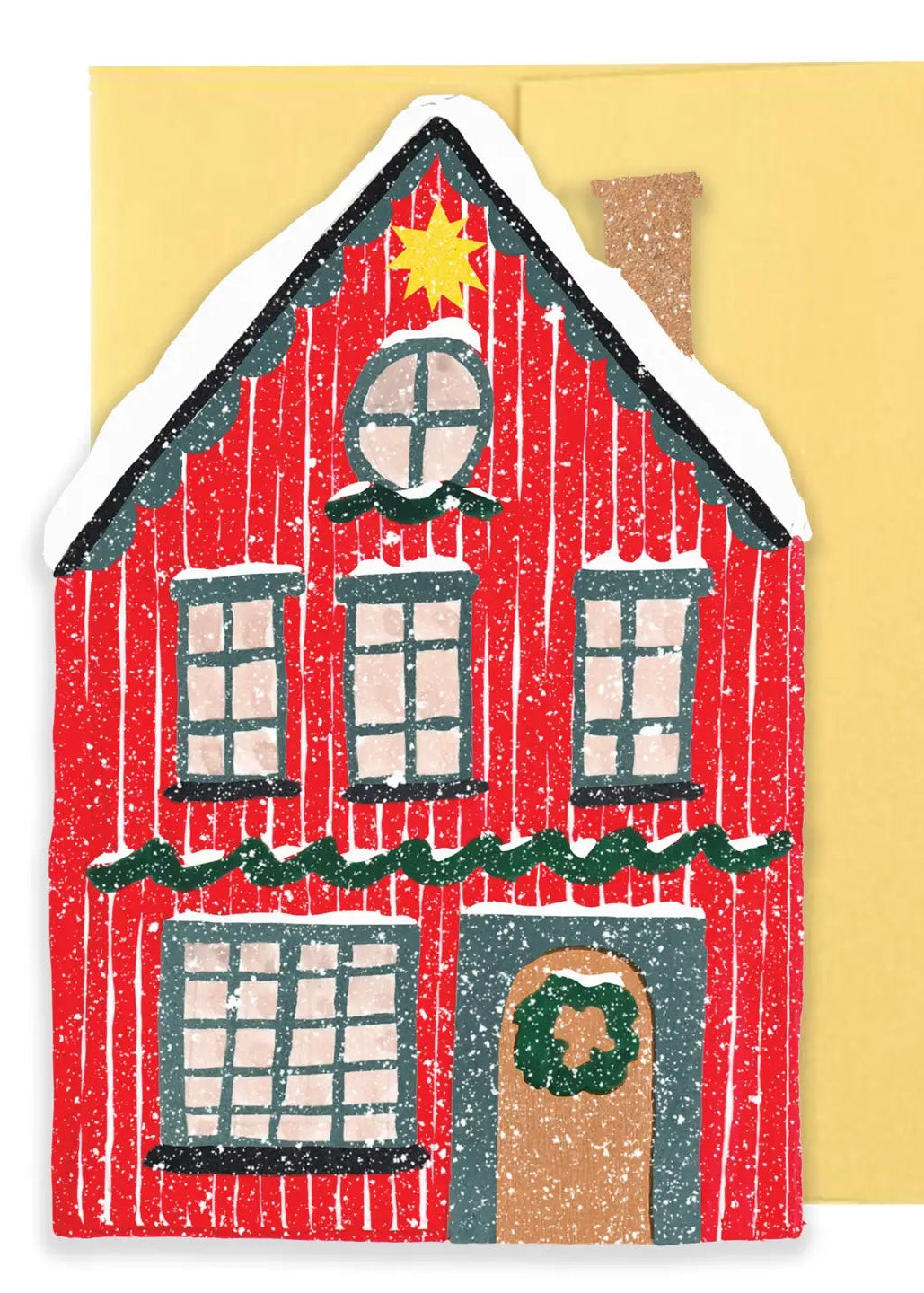 A handcrafted Christmas house cutout card or ornament in red with white snow, a yellow star, green garland, and a brown door, shown in front of a yellow envelope.