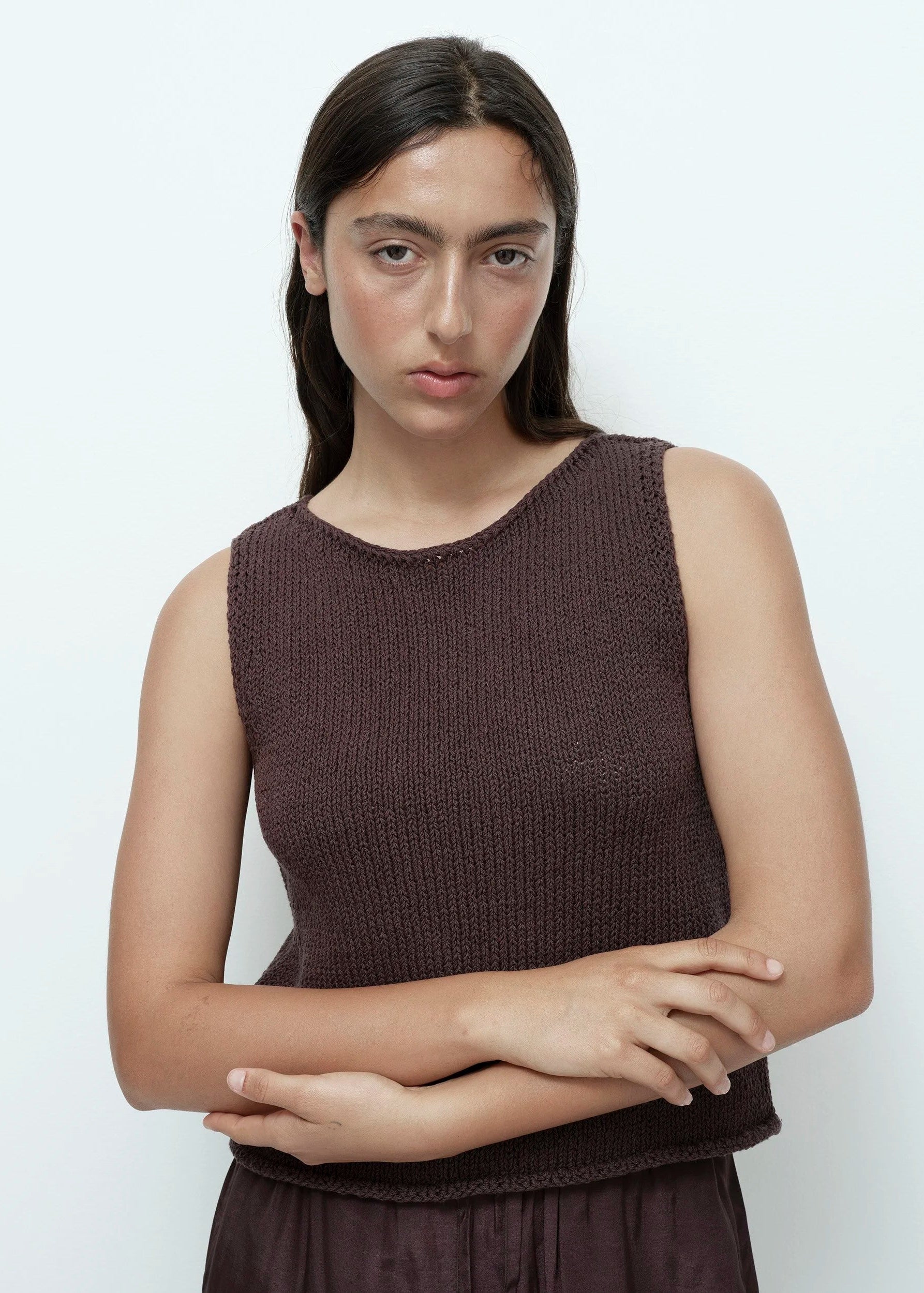 Woman wearing a brown sleeveless top against a white background