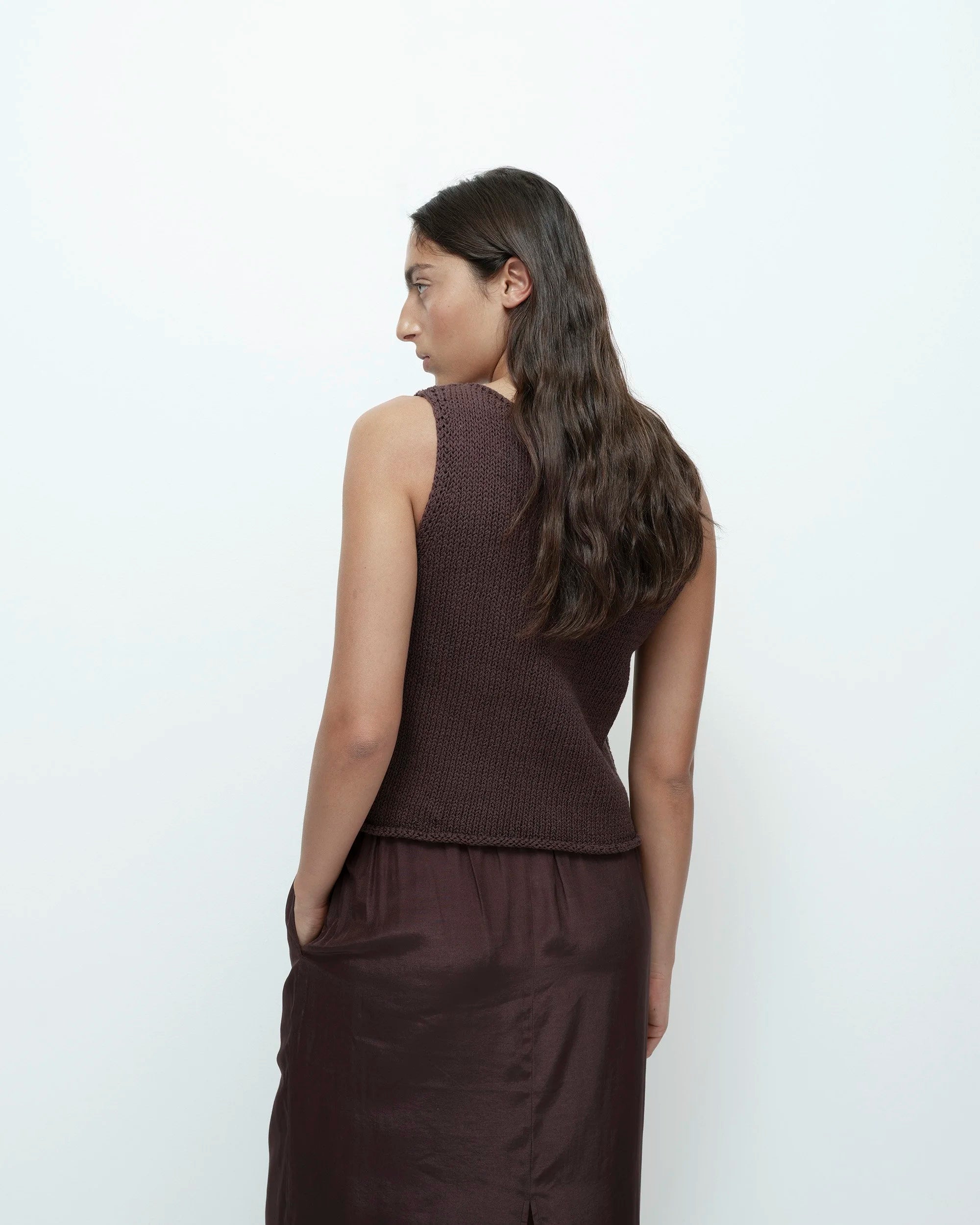 Woman wearing a brown sleeveless top and pants on a white background