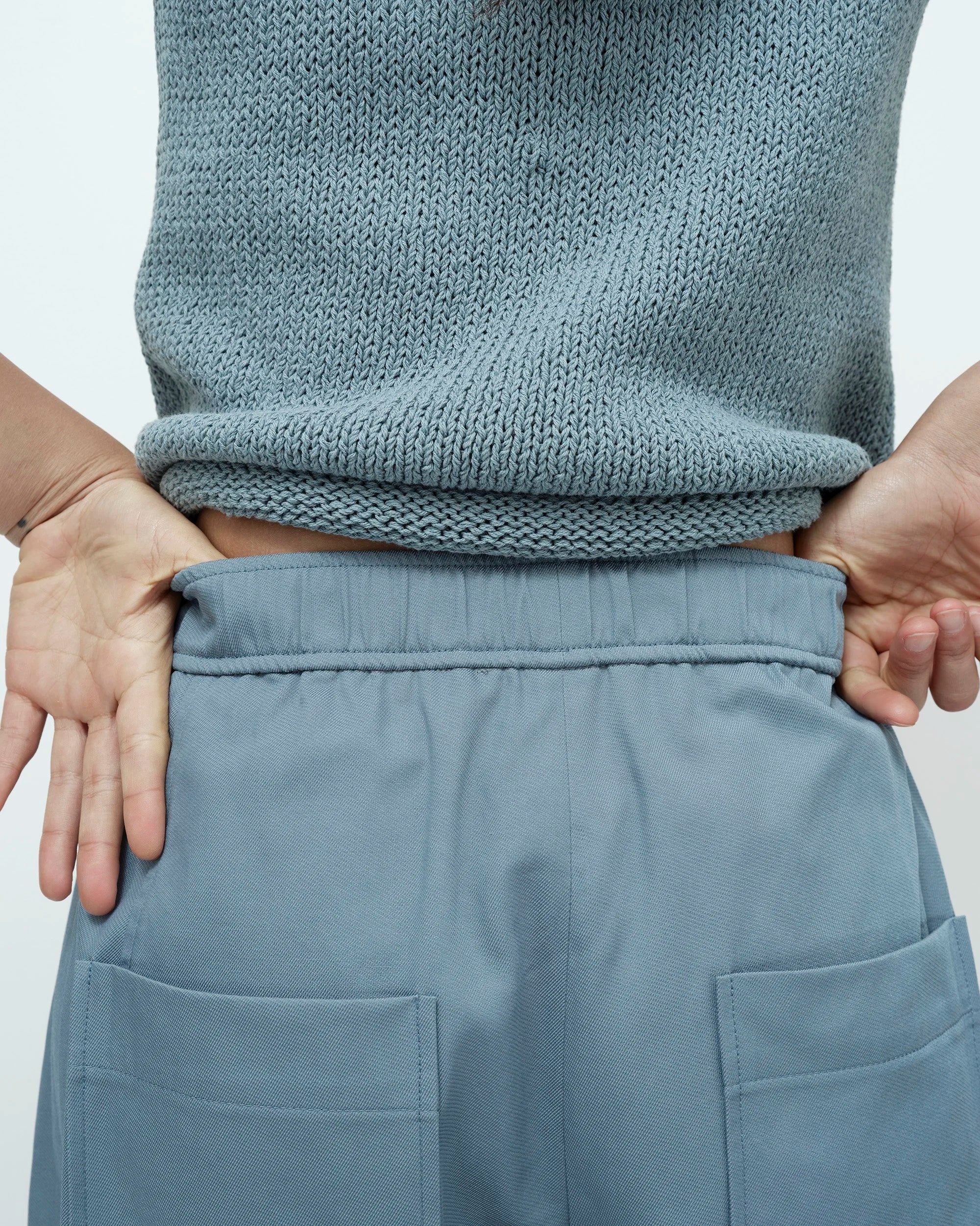 Person wearing a matching blue knit sweater and pants against a light gray background