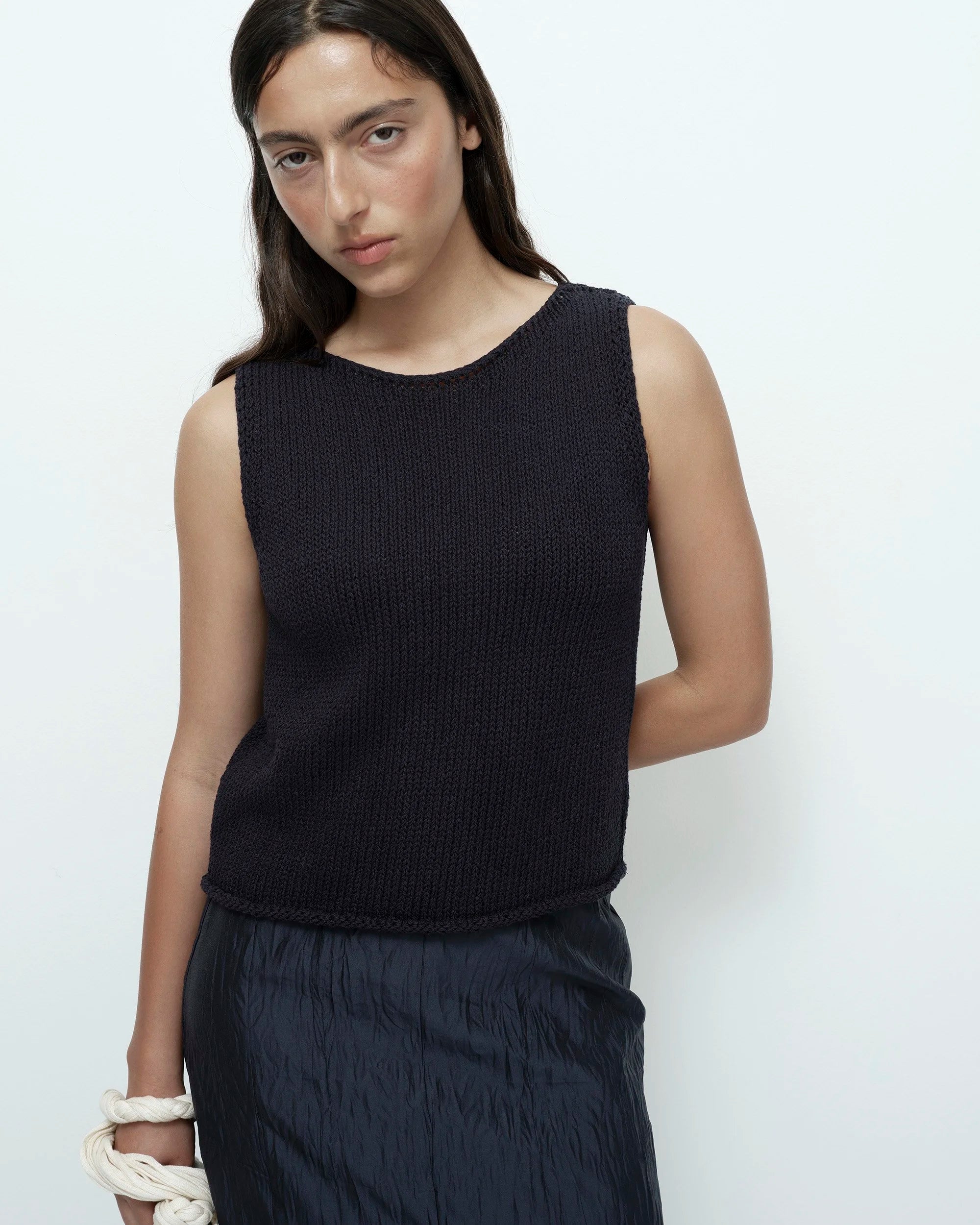    Woman wearing a navy sleeveless top and dark skirt on a white background