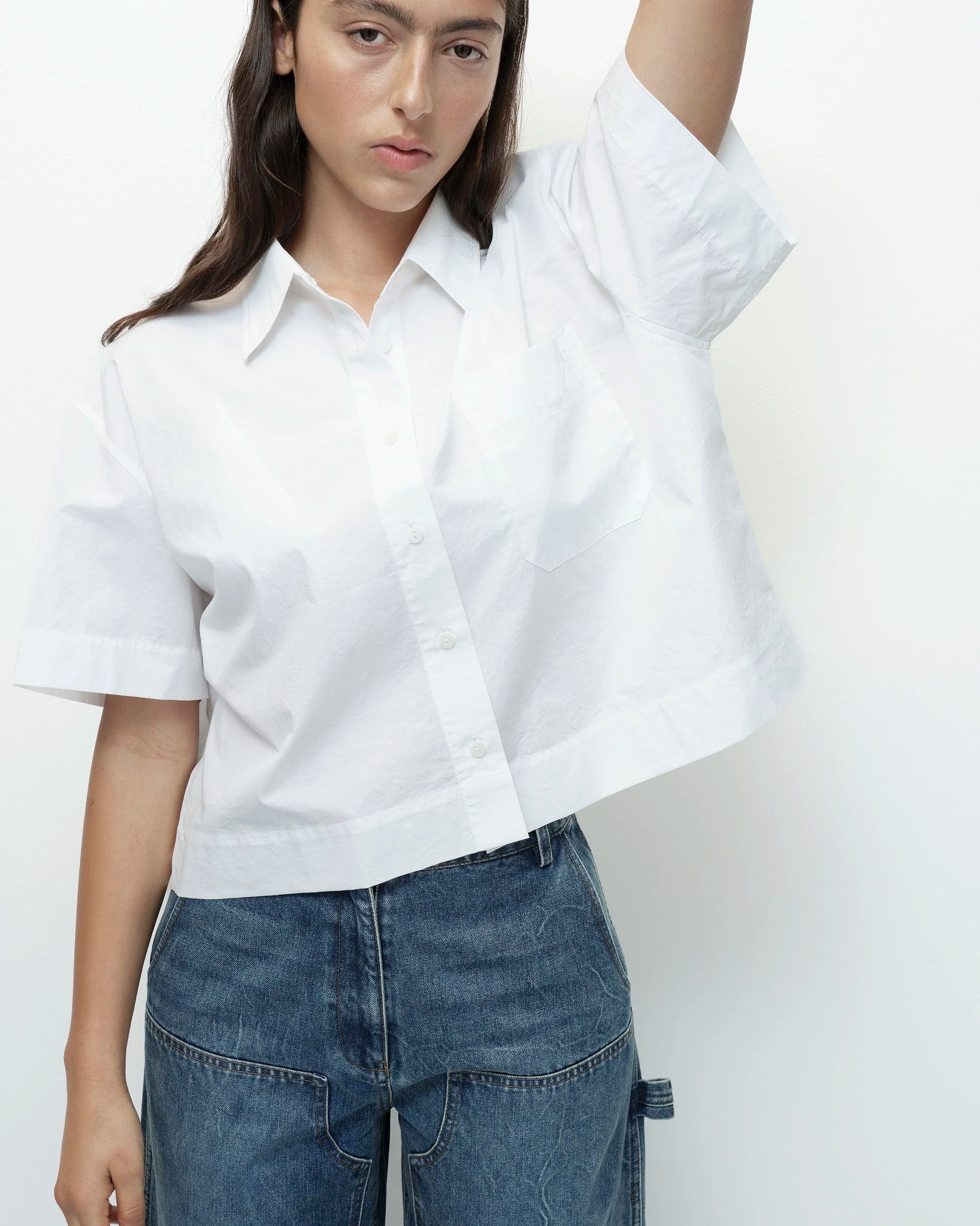 Person wearing a white shirt and blue jeans against a plain background