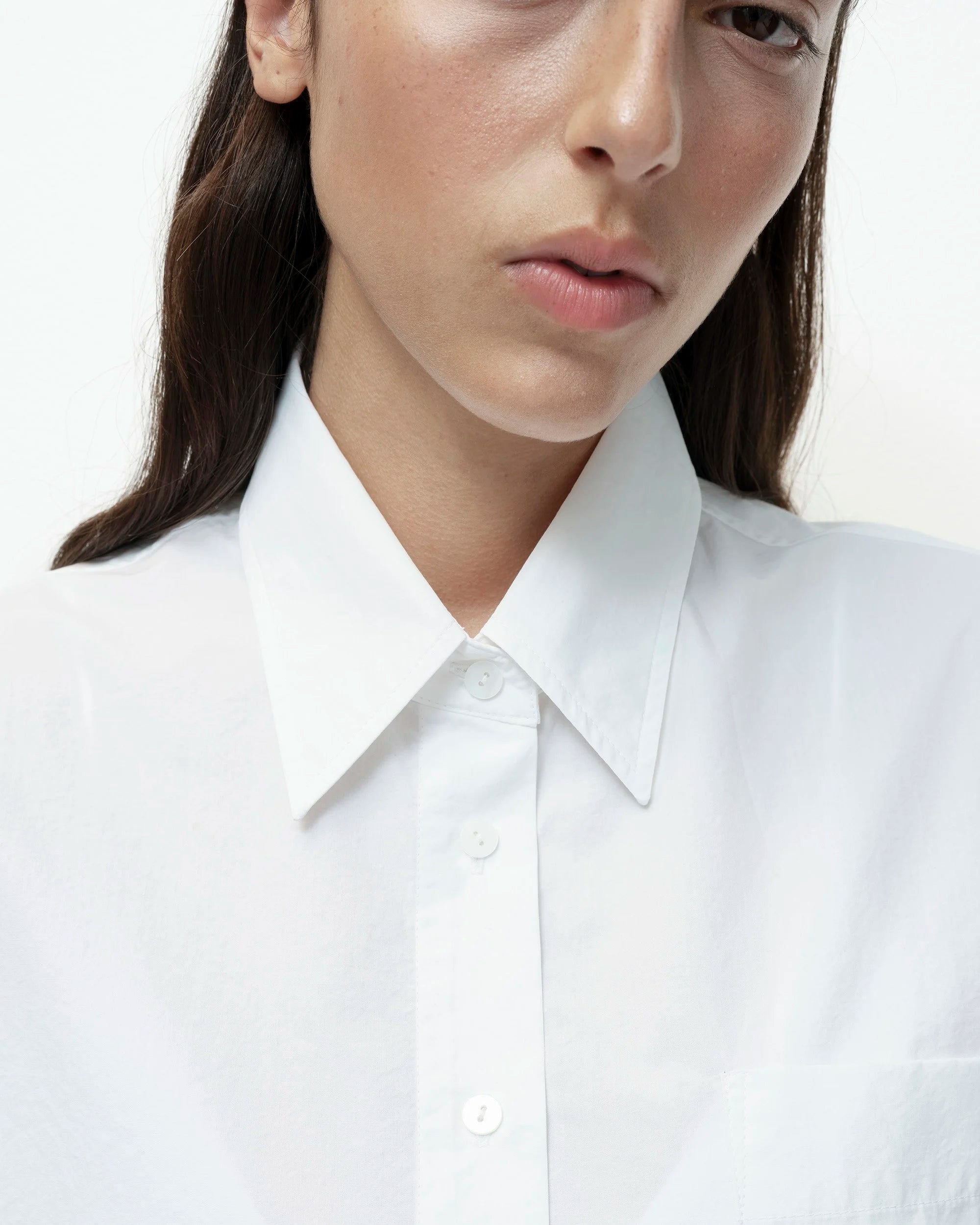 Close-up of a person wearing a white shirt with a blurred background