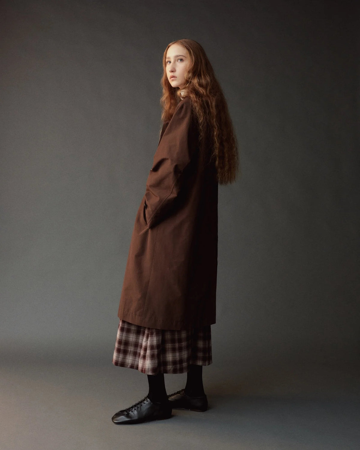 person modeling long brown trench coat, side view