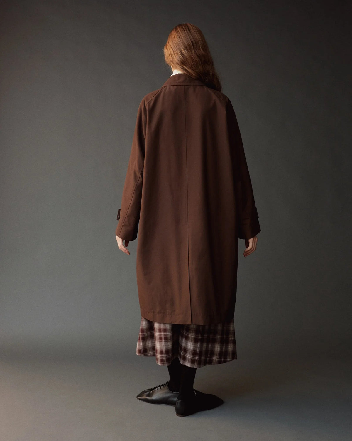 person modeling long brown trench coat, back view
