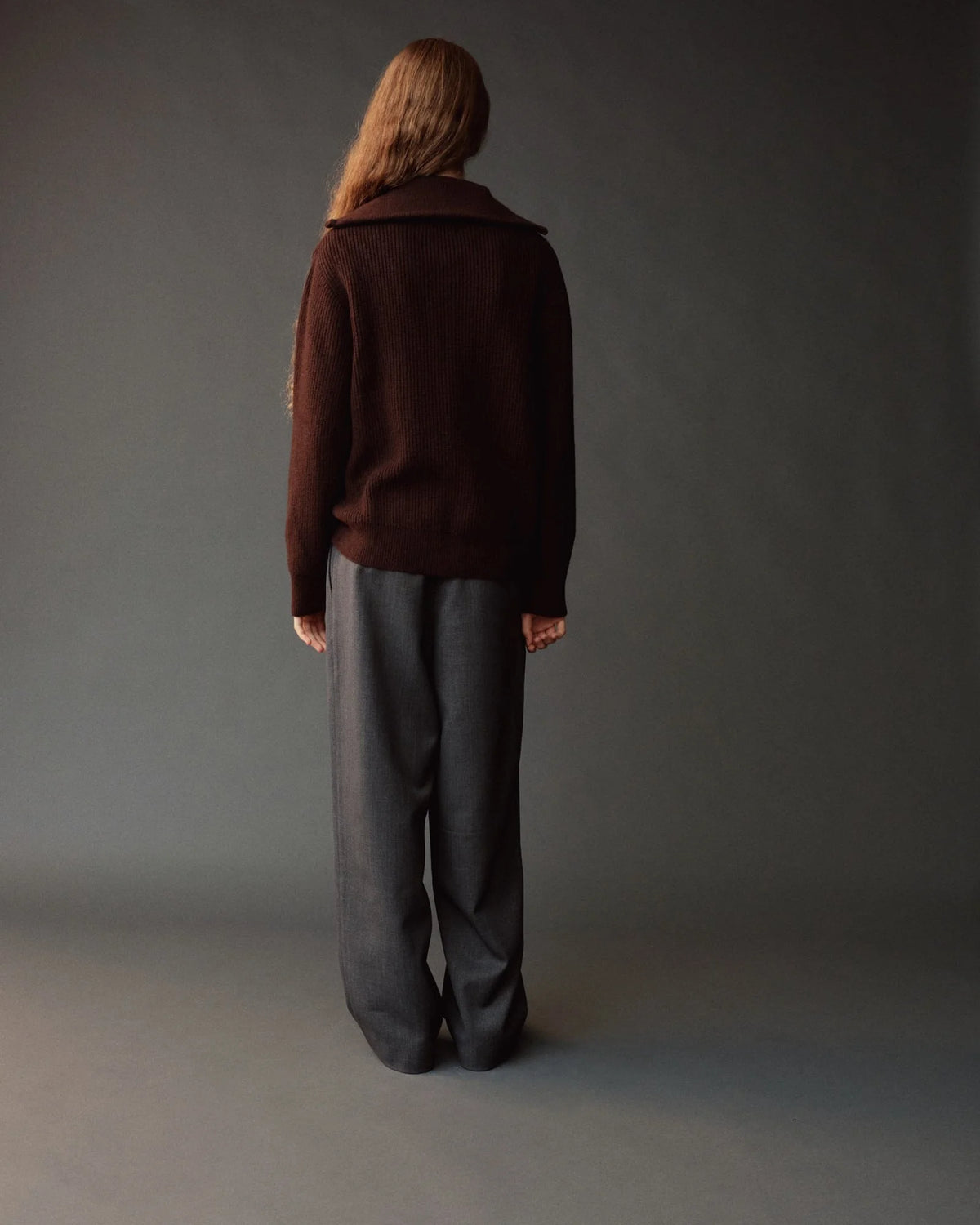 brown half zip sweater on model from back, wearing gray pants