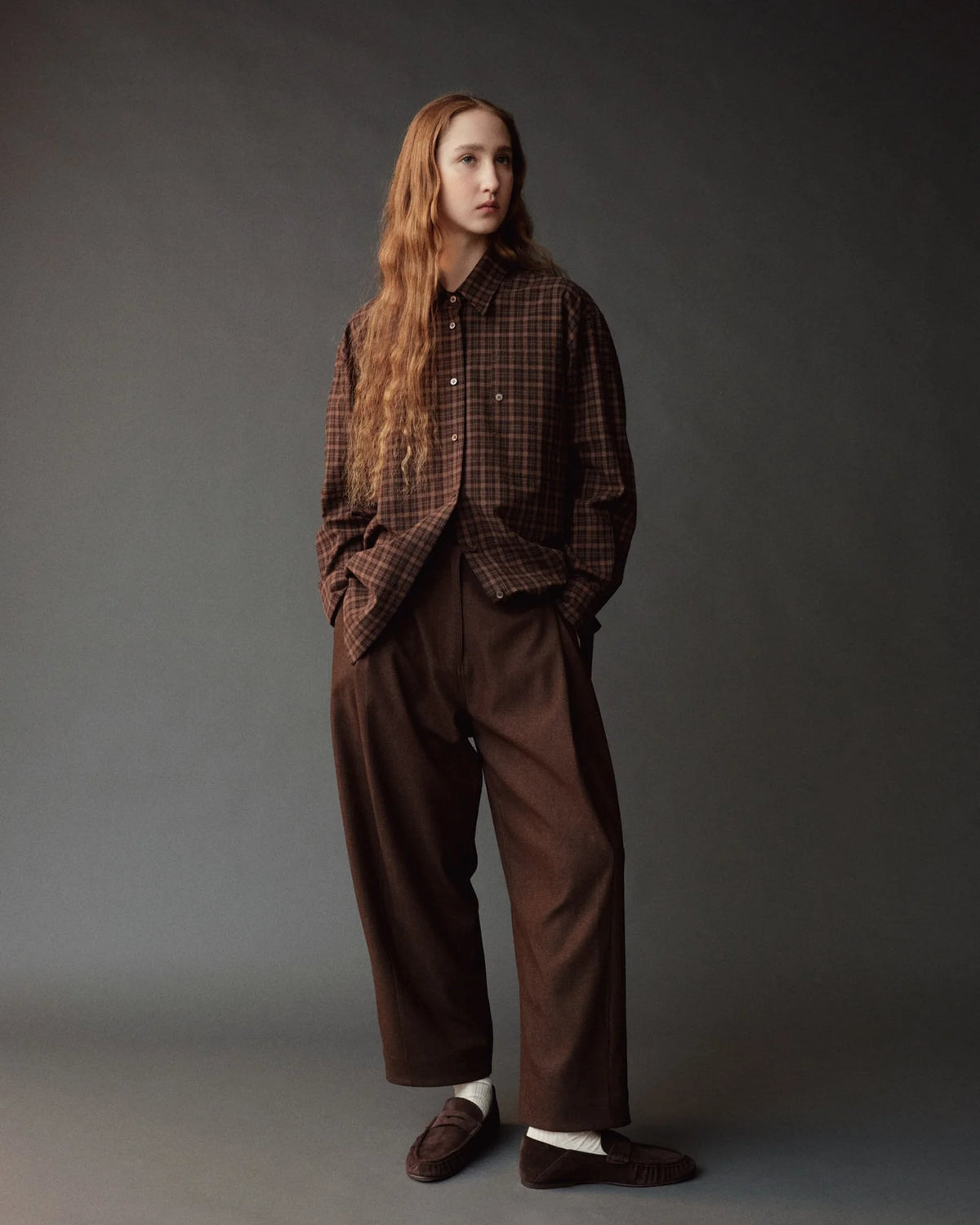 model wearing brown pants and brown plaid shirt