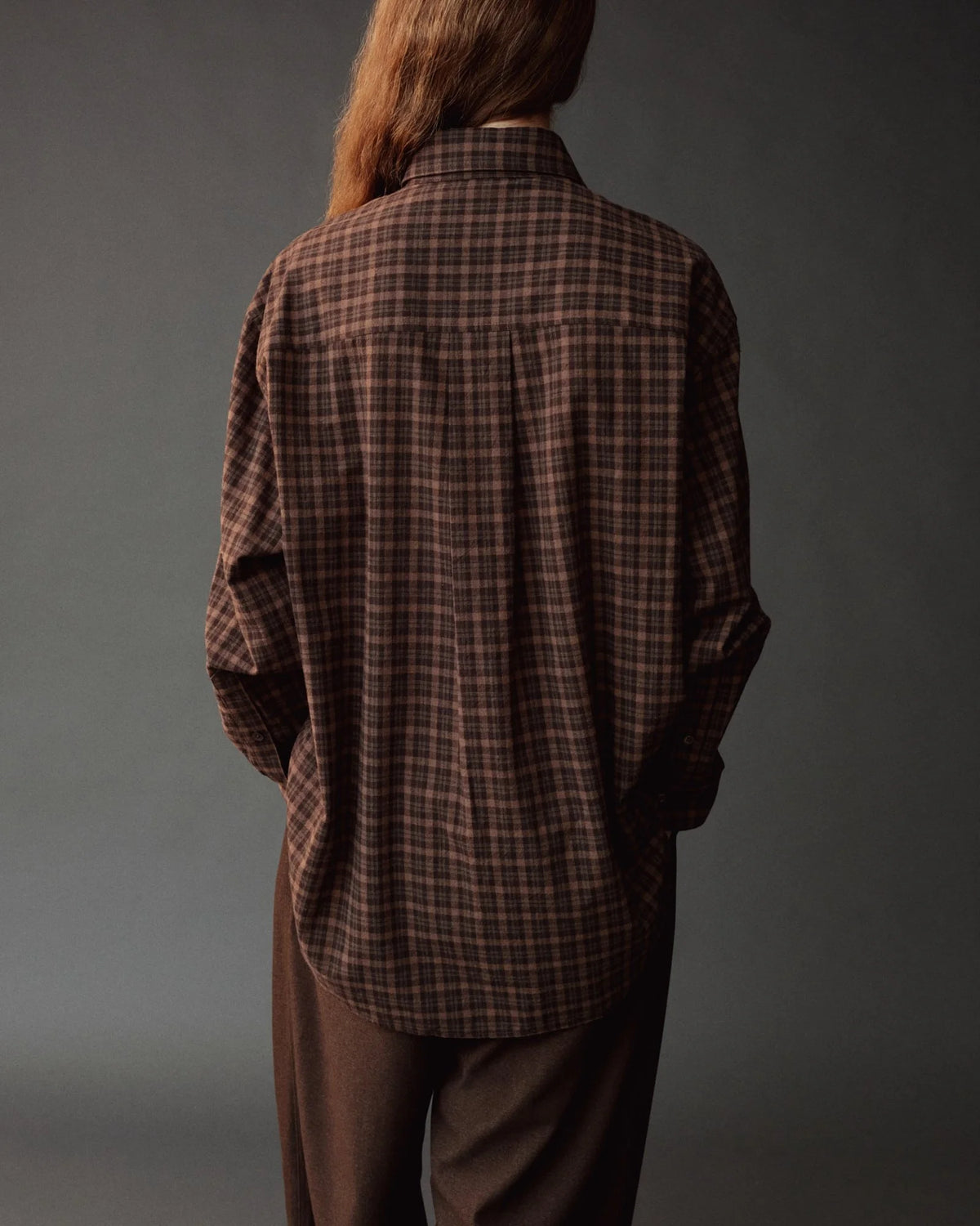 oversized brown plaid shirt on model wearing brown pants from back