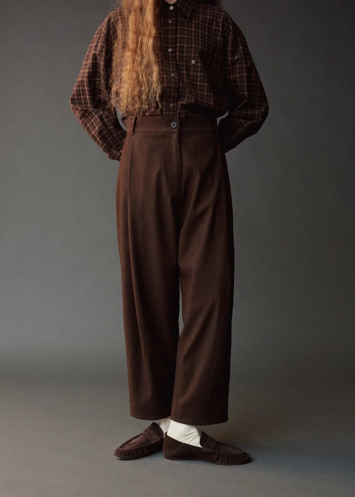 model wearing brown pants and brown plaid shirt