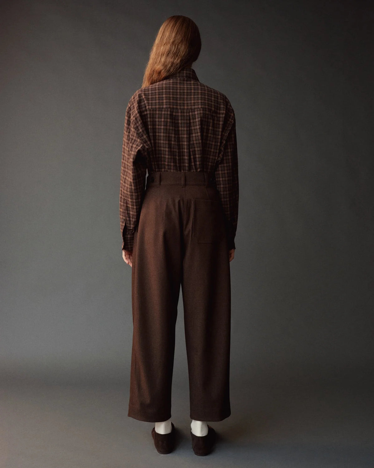 model wearing brown pants and brown plaid shirt from back