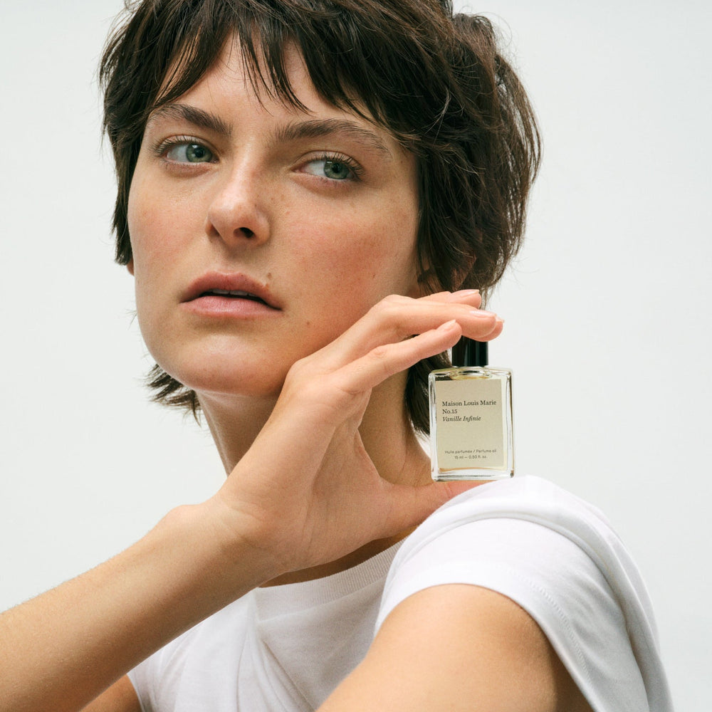 Woman holding a perfume bottle with a plain background