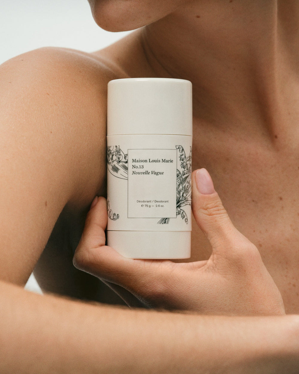 Person holding a cylindrical product with branding against a neutral background