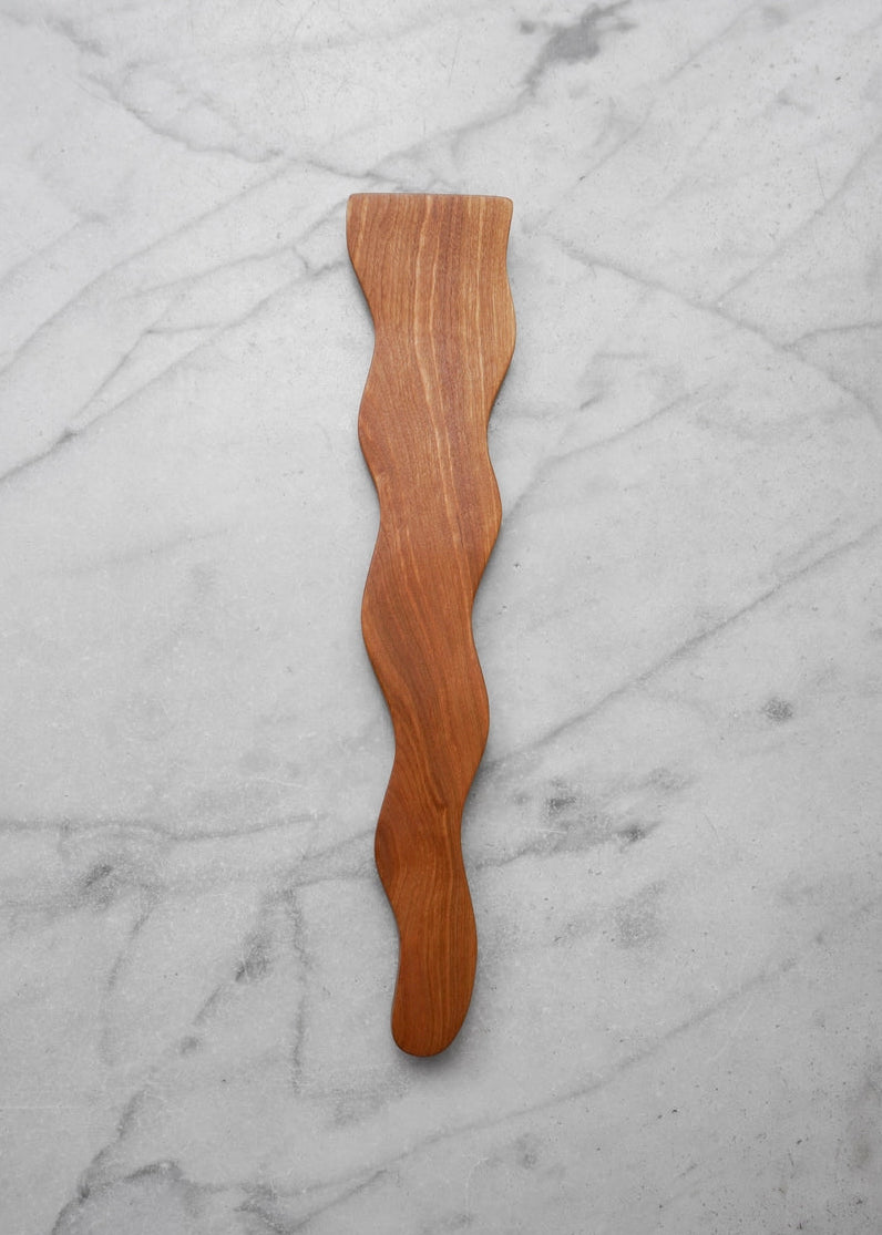 Wooden spatula with wavy design on a marble surface