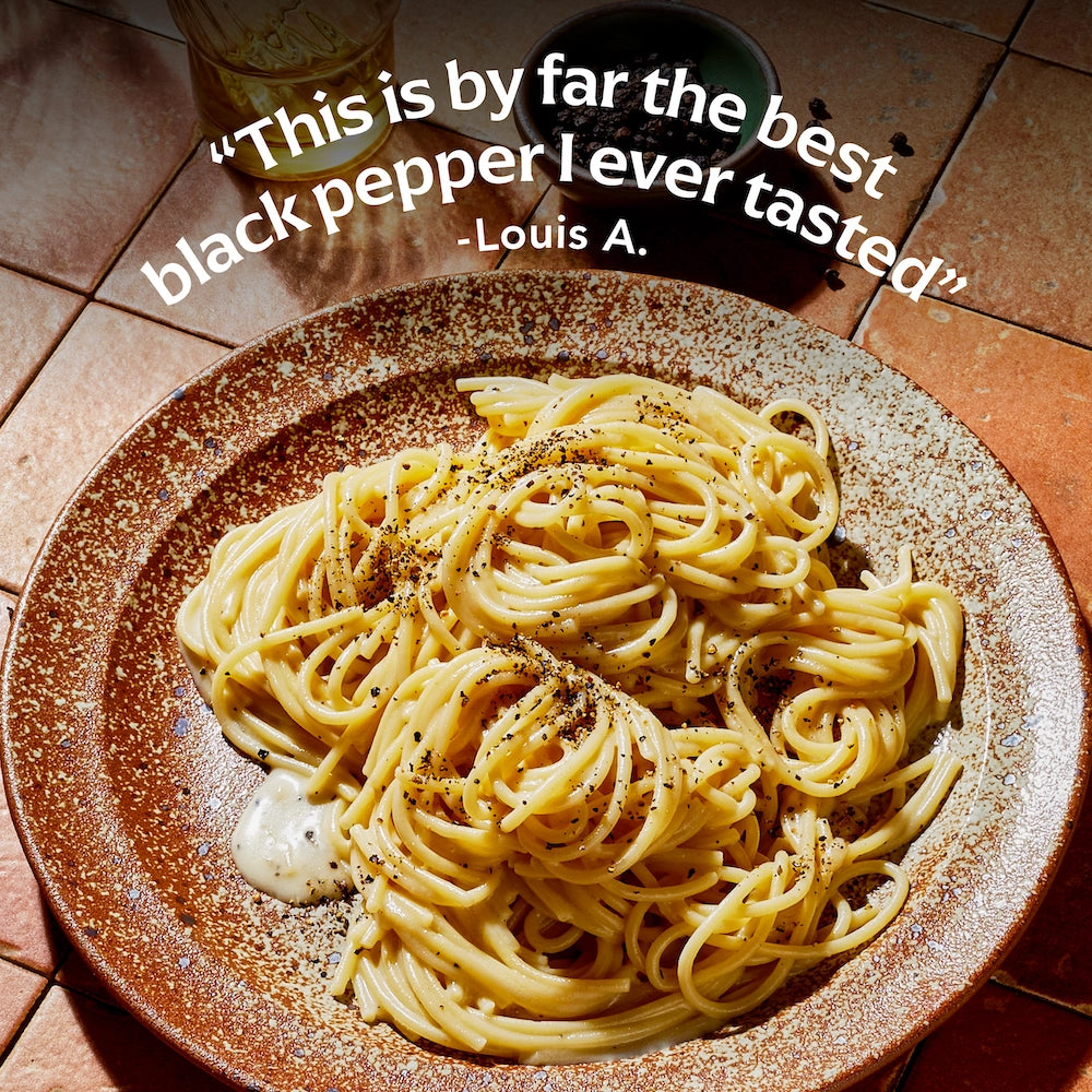 Spaghetti dish on a textured plate with text praising the black pepper.