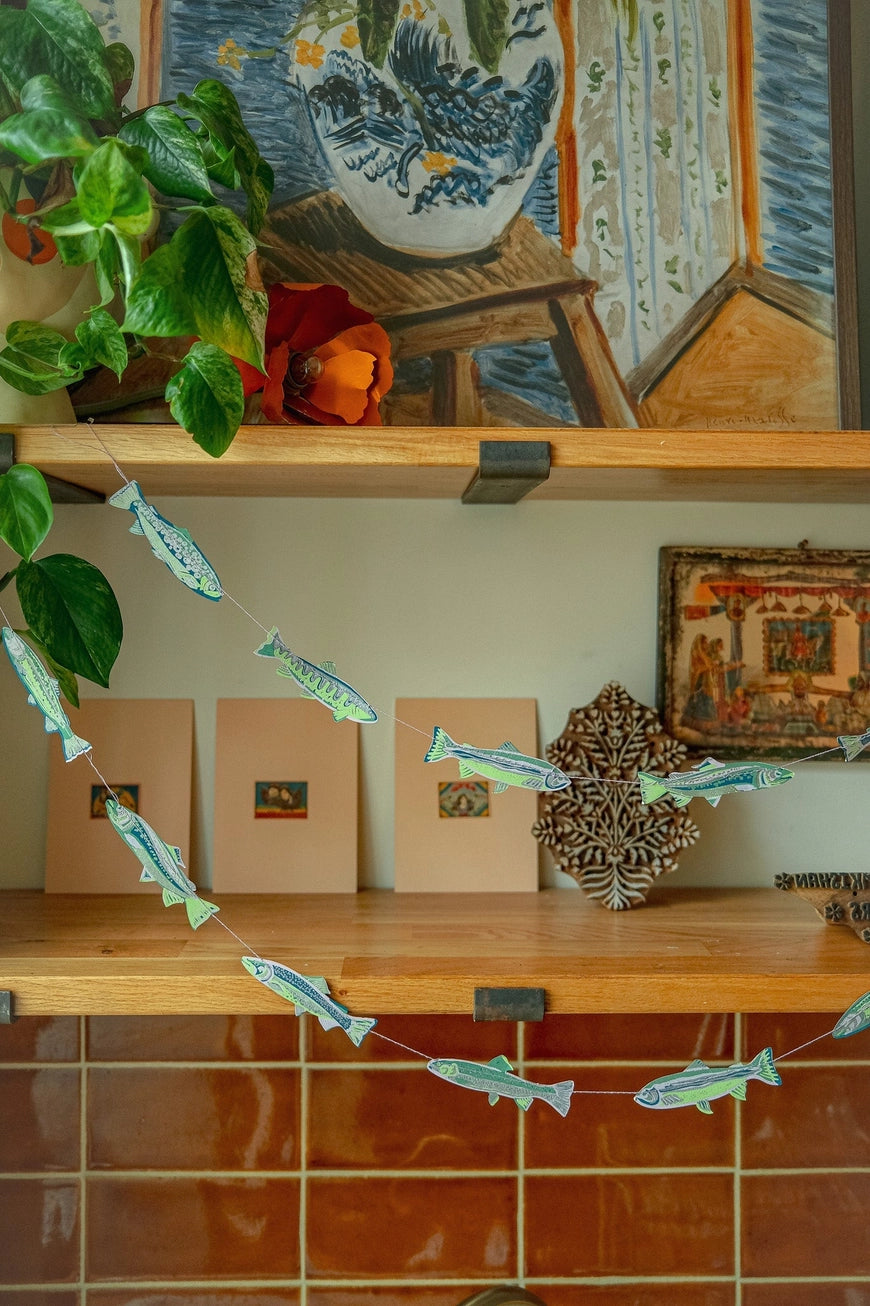 Wooden shelf with decorative items including a plant, framed pictures, and a wooden star-shaped object.