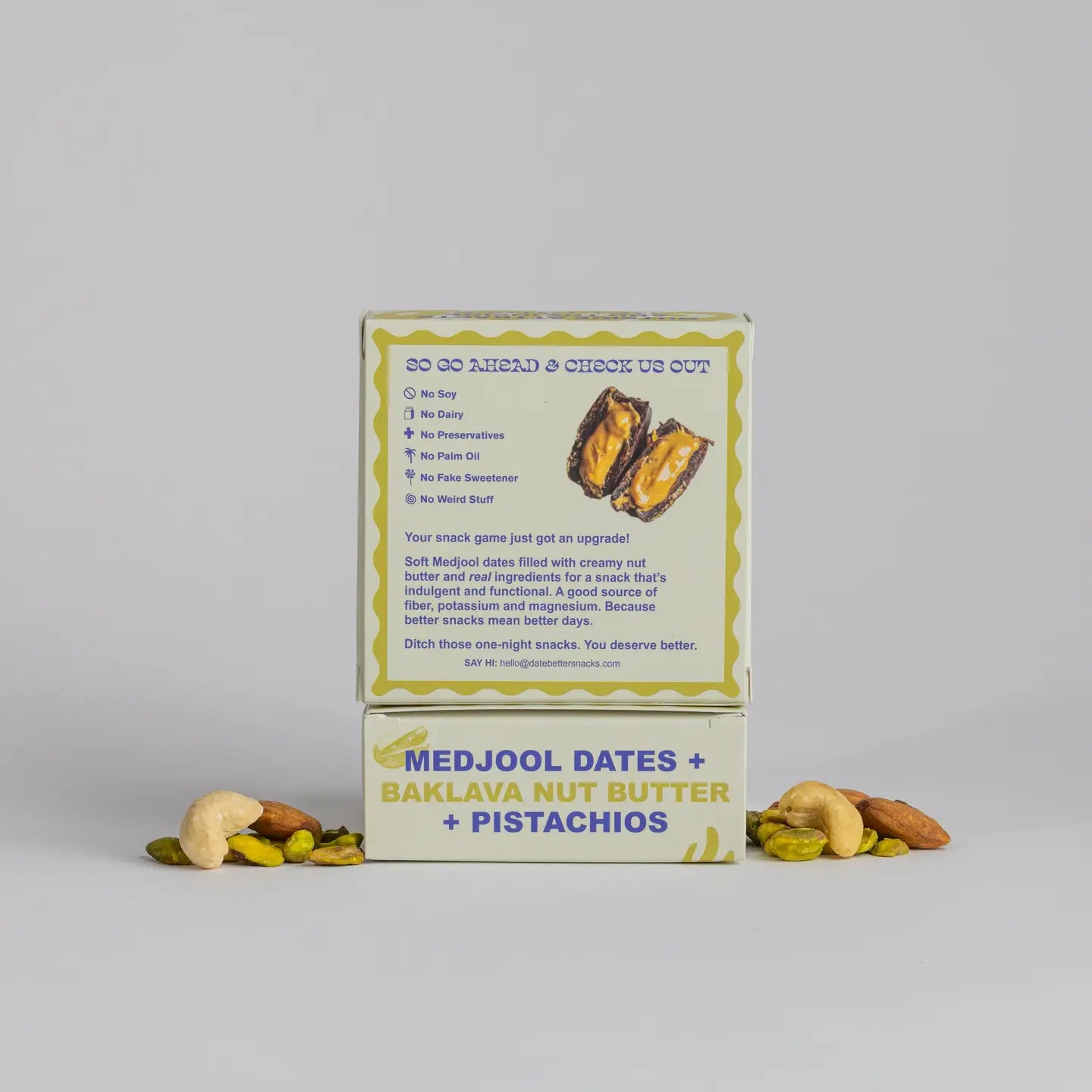 Box of Medjool dates, Baklava nut butter, and pistachios with a gray background