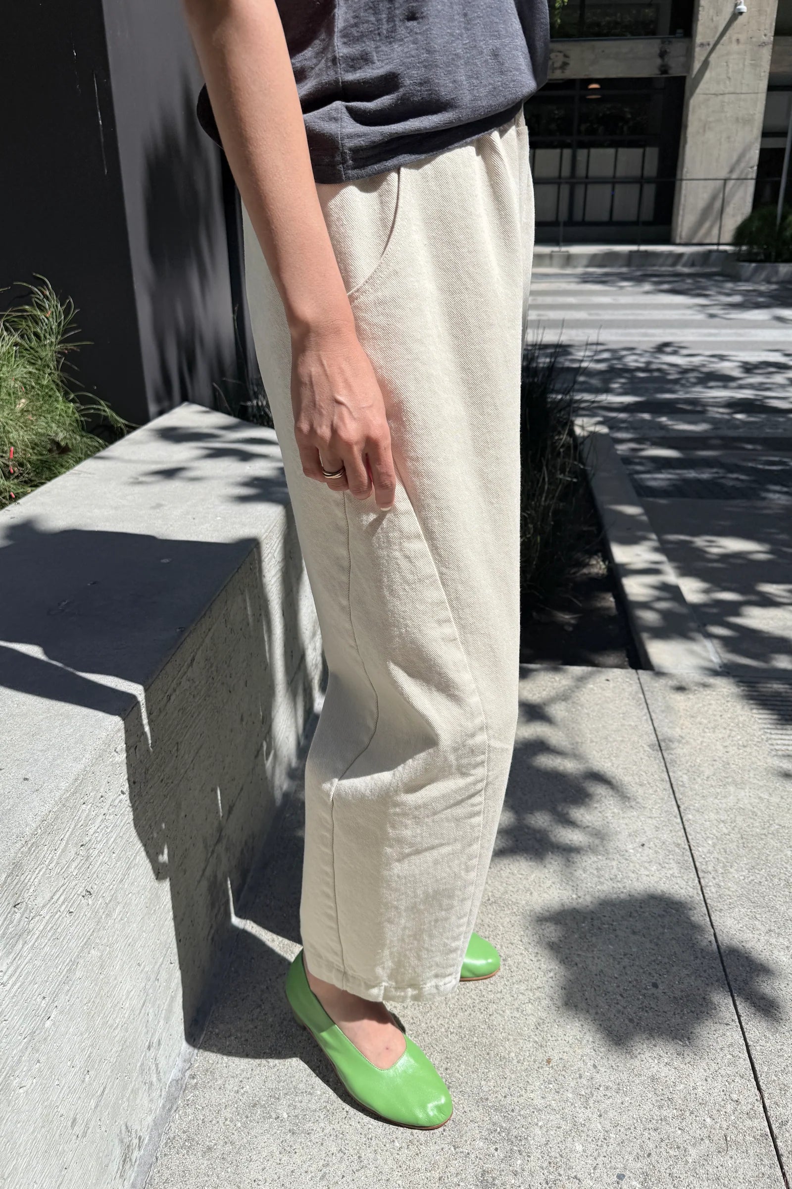 Person wearing white pants and green shoes on a sidewalk