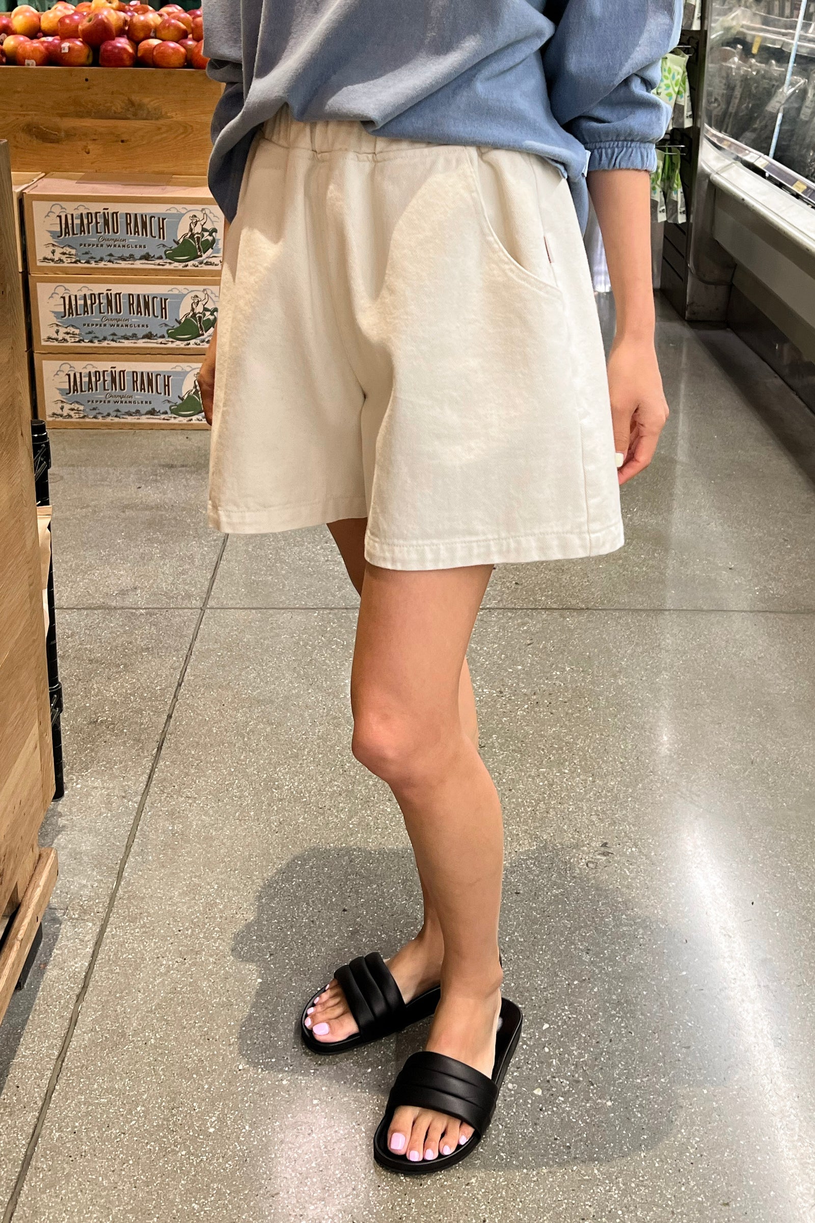 Person wearing beige shorts and black sandals in a store setting