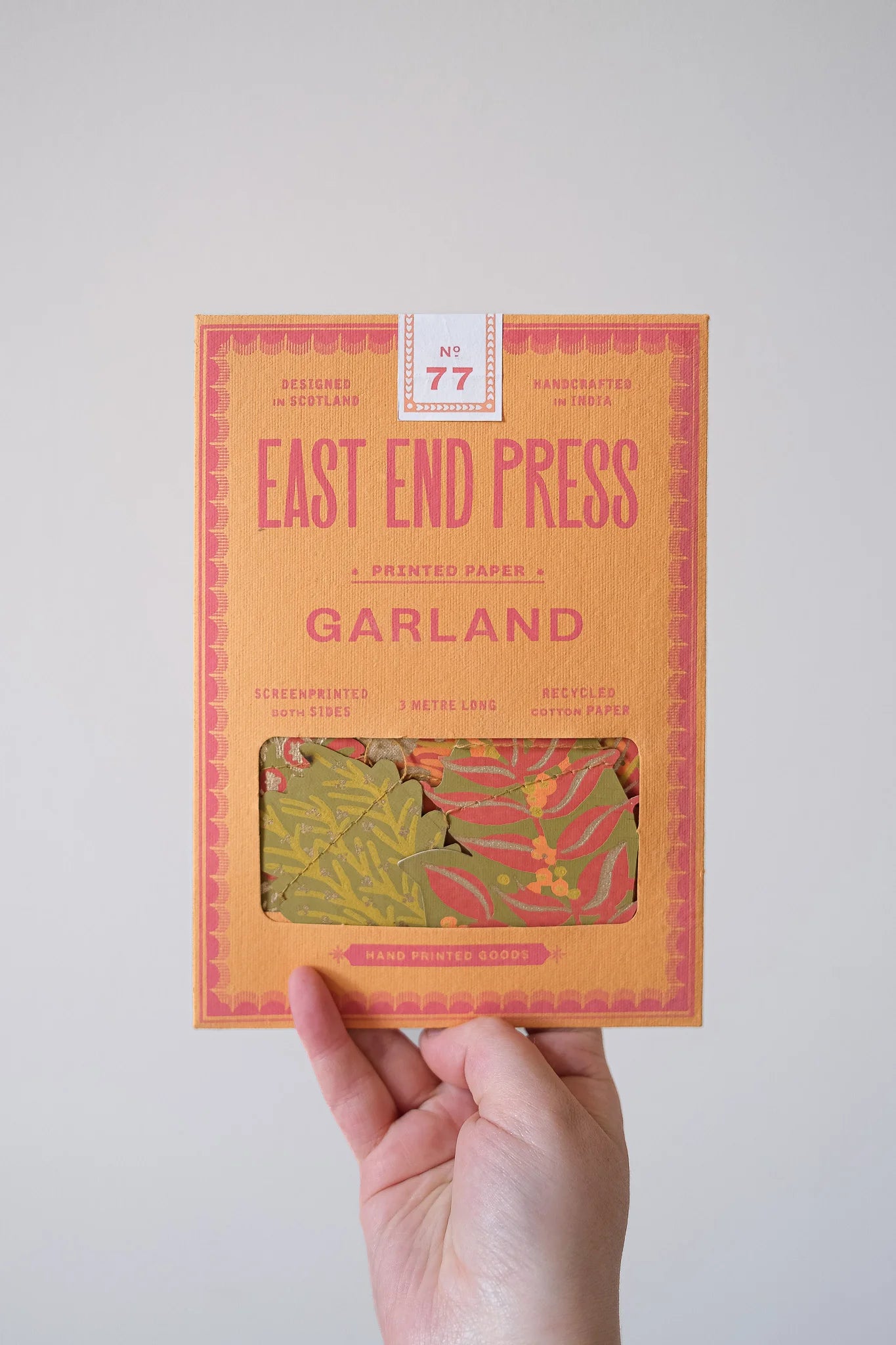 Hand holding a package of East End Press Garland printed paper against a plain background