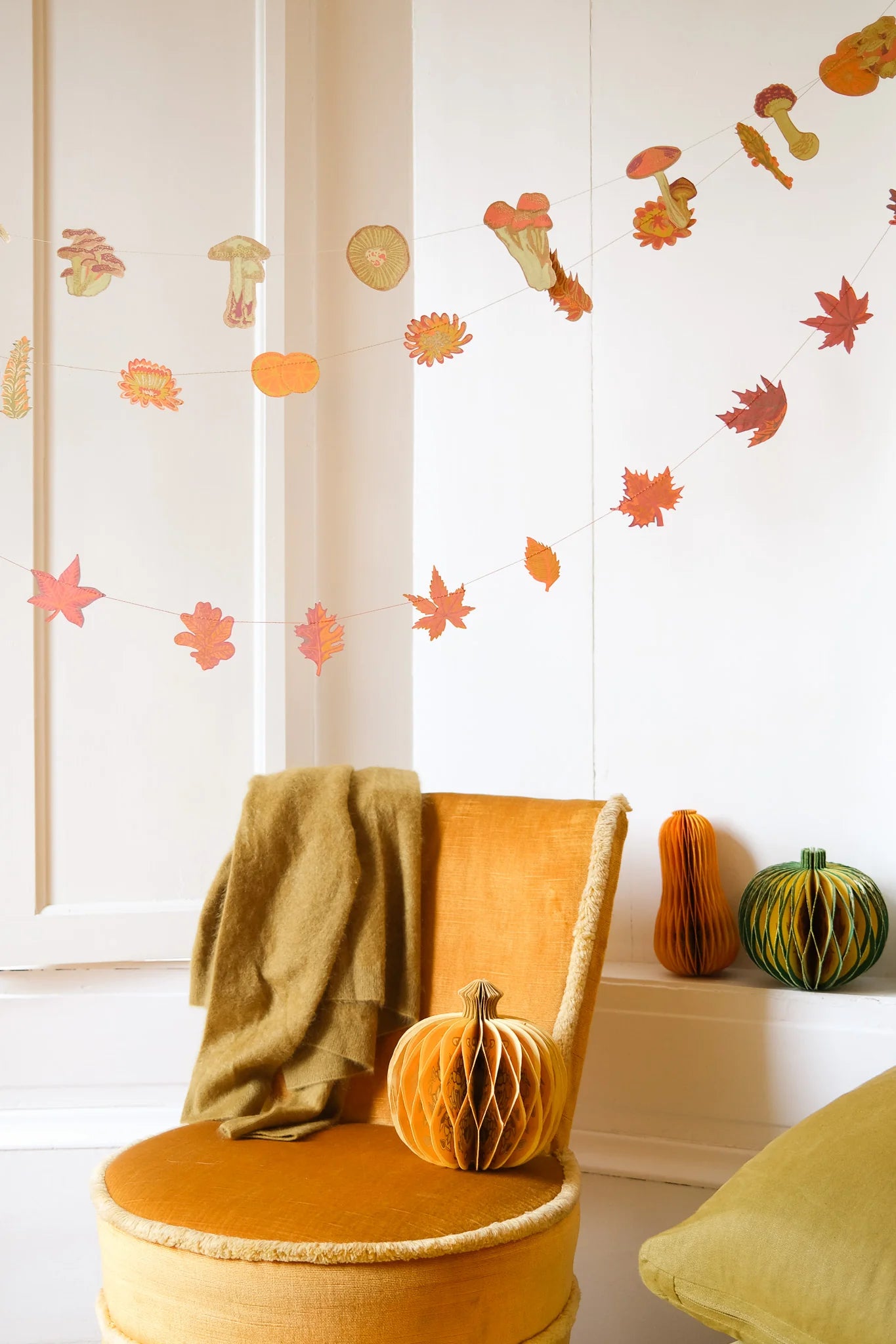 Decorative autumn-themed wall stickers on a white wall with a chair and pumpkins.