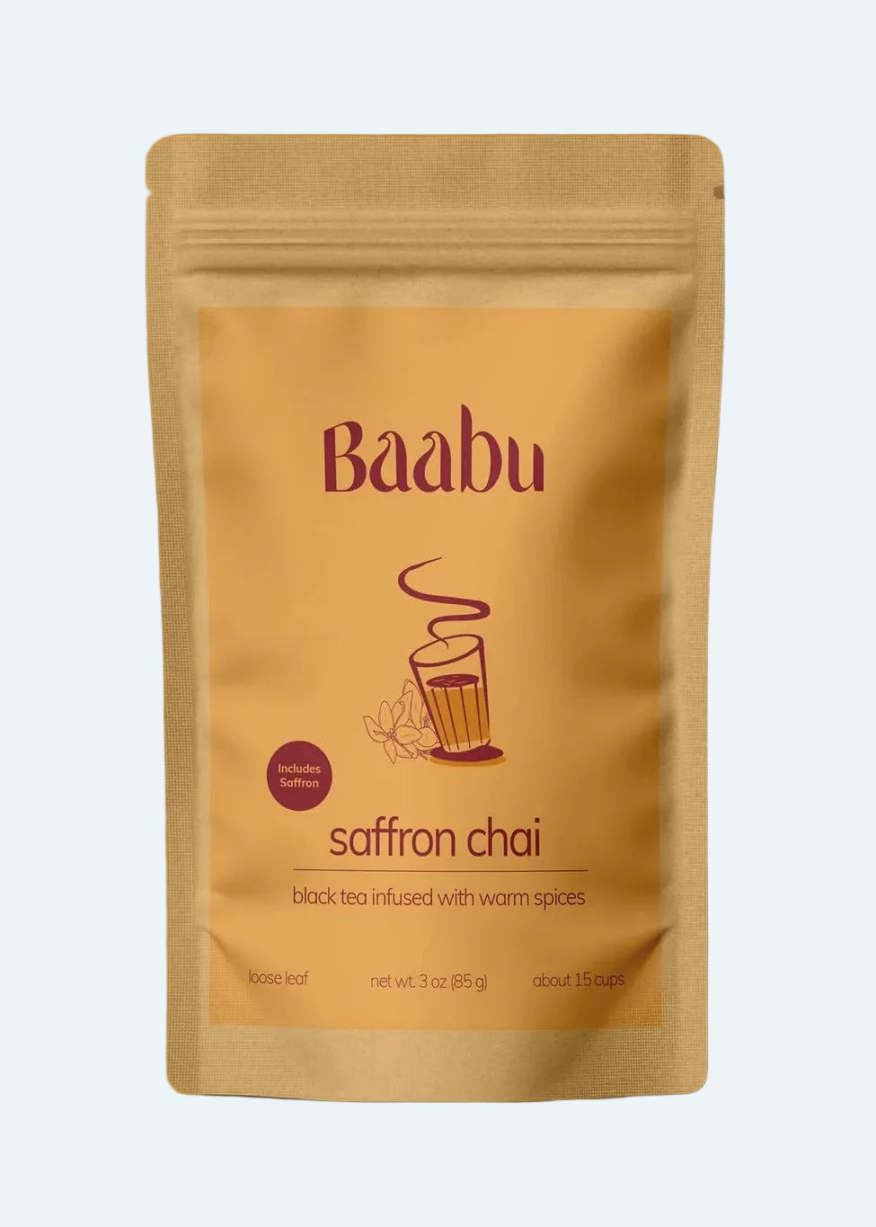 A stand-up pouch of Baabu Saffron Chai tea on a solid warm orange background. The packaging is a light tan kraft paper style with dark red text and a small illustration of a cup with steam.