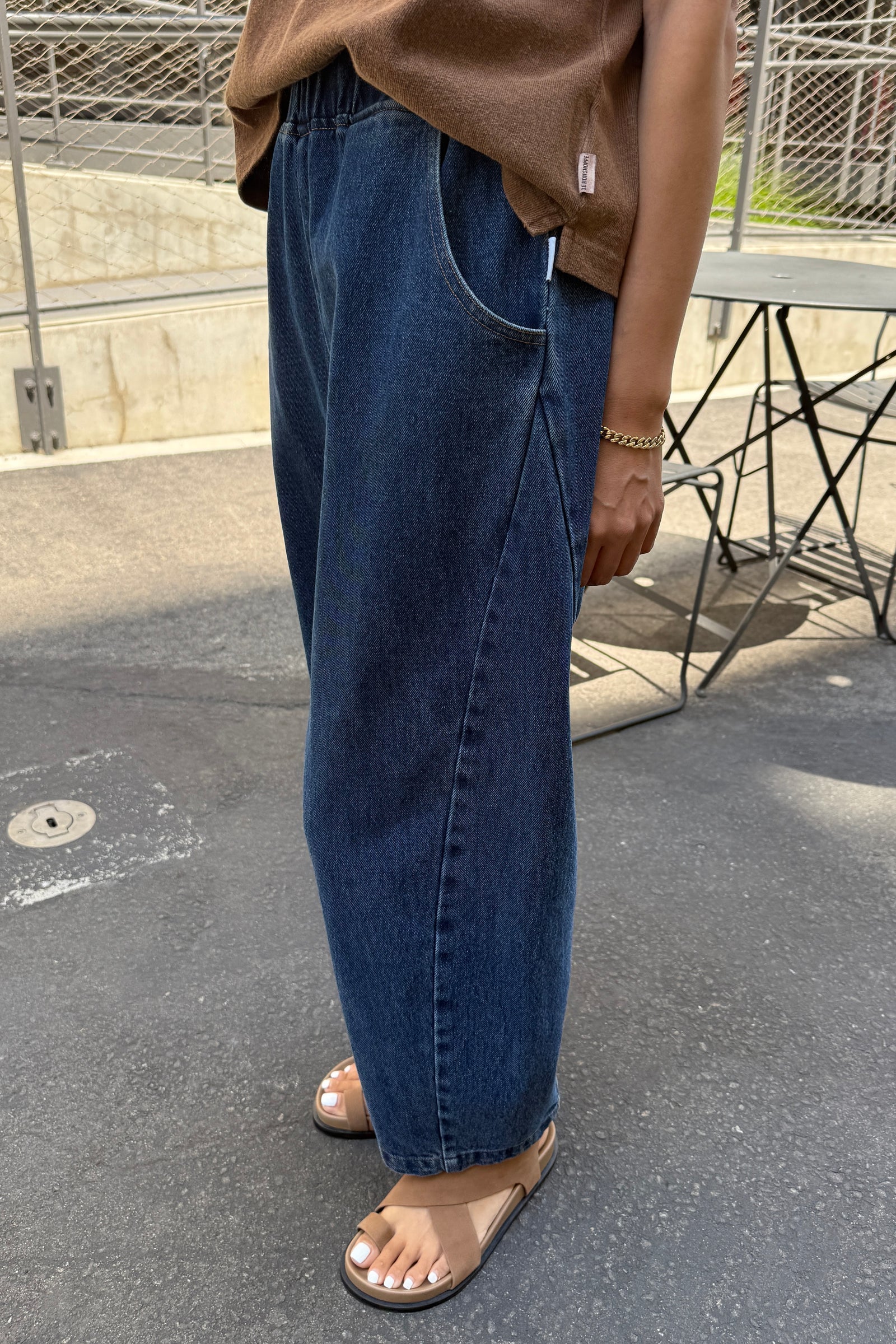 Person wearing blue jeans and a brown top on a street.