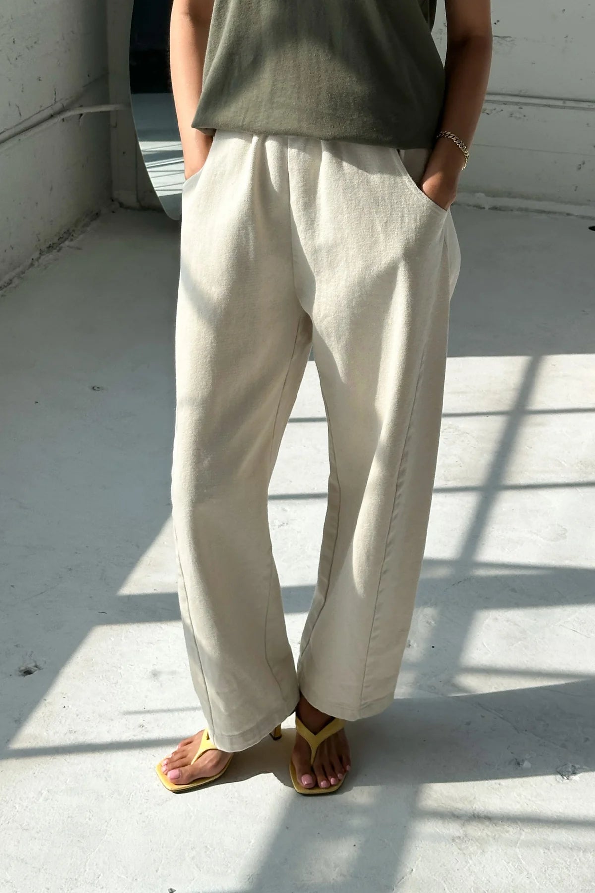 Person wearing beige wide-leg pants and a green top on a light-colored floor.