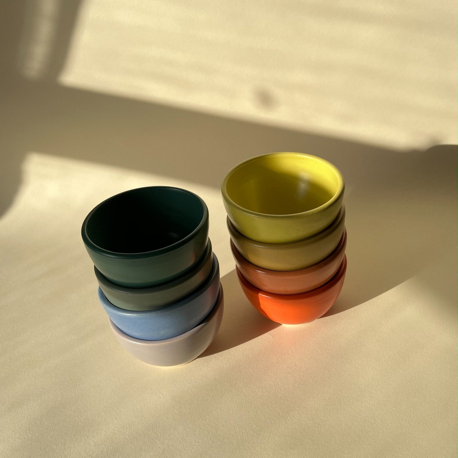 two stacks  of handmade bowls in rainbow colors