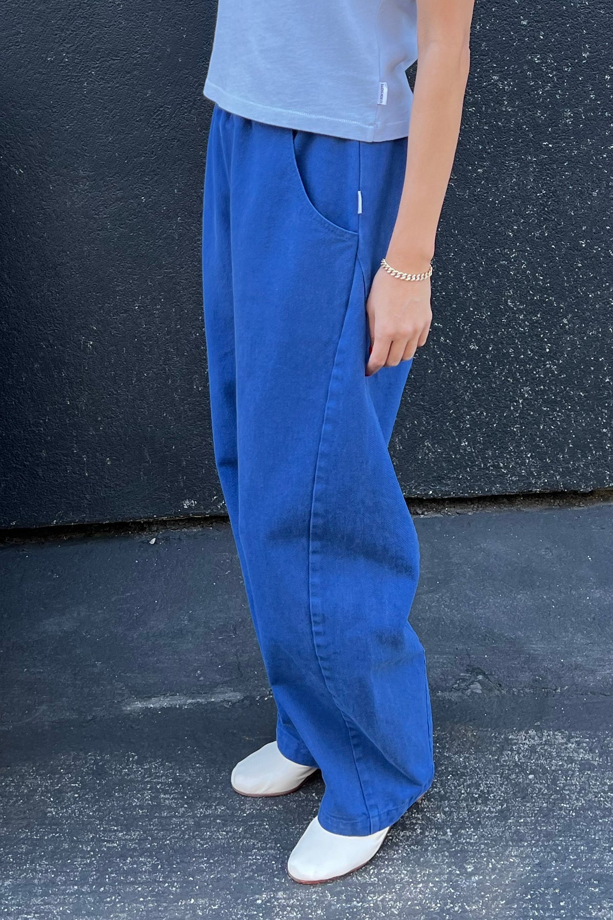 Person wearing blue pants and white shoes against a dark background