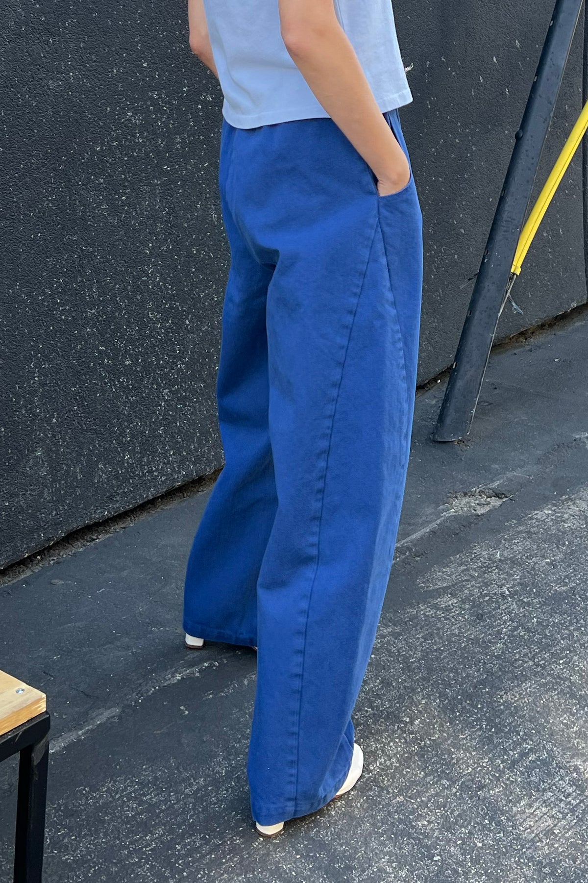 Person wearing blue pants standing on a concrete surface with a dark wall in the background