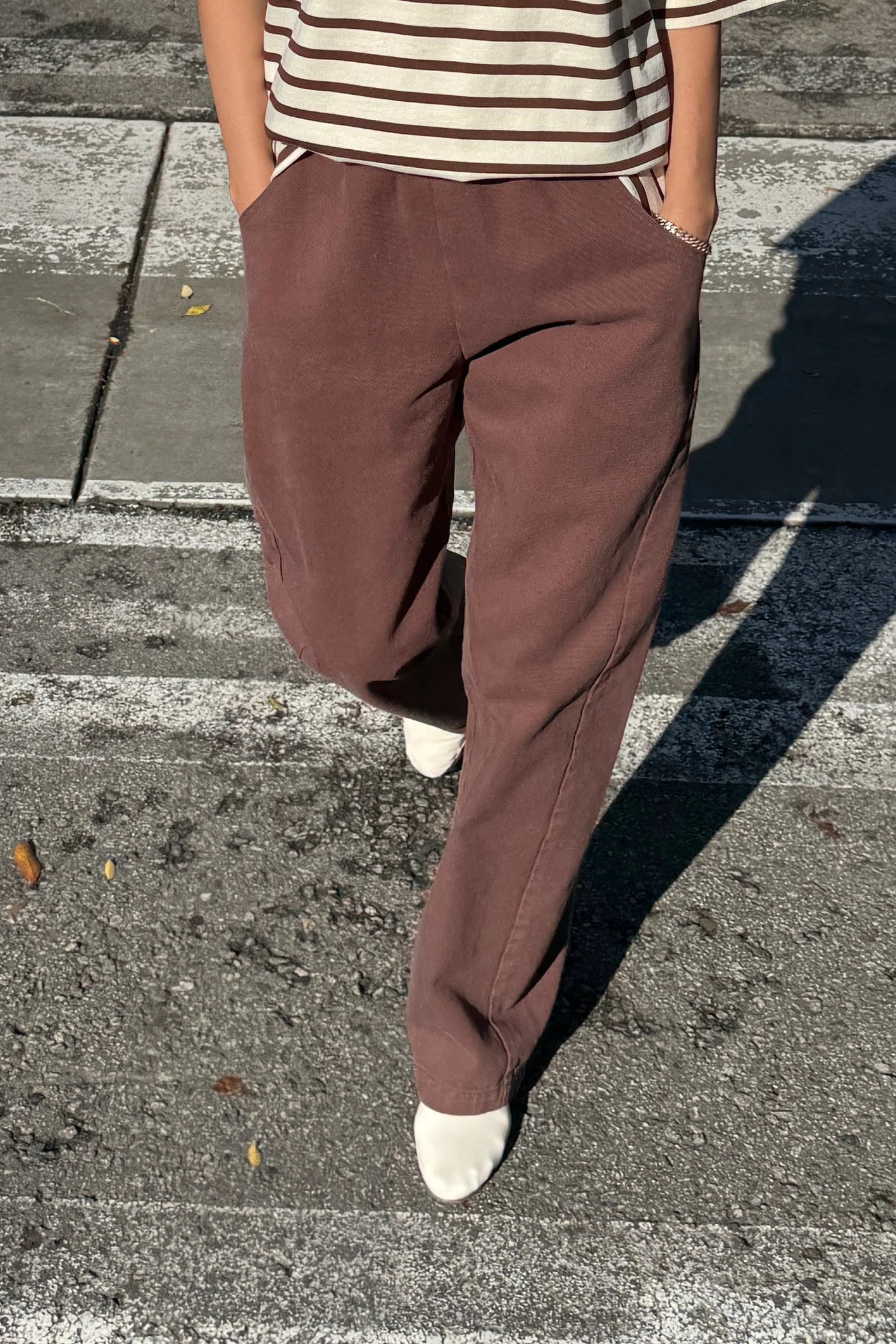 Person wearing brown pants and a striped shirt on a street.