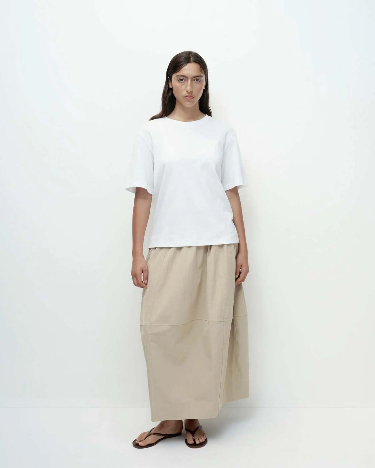 Person wearing a white top and beige skirt on a white background