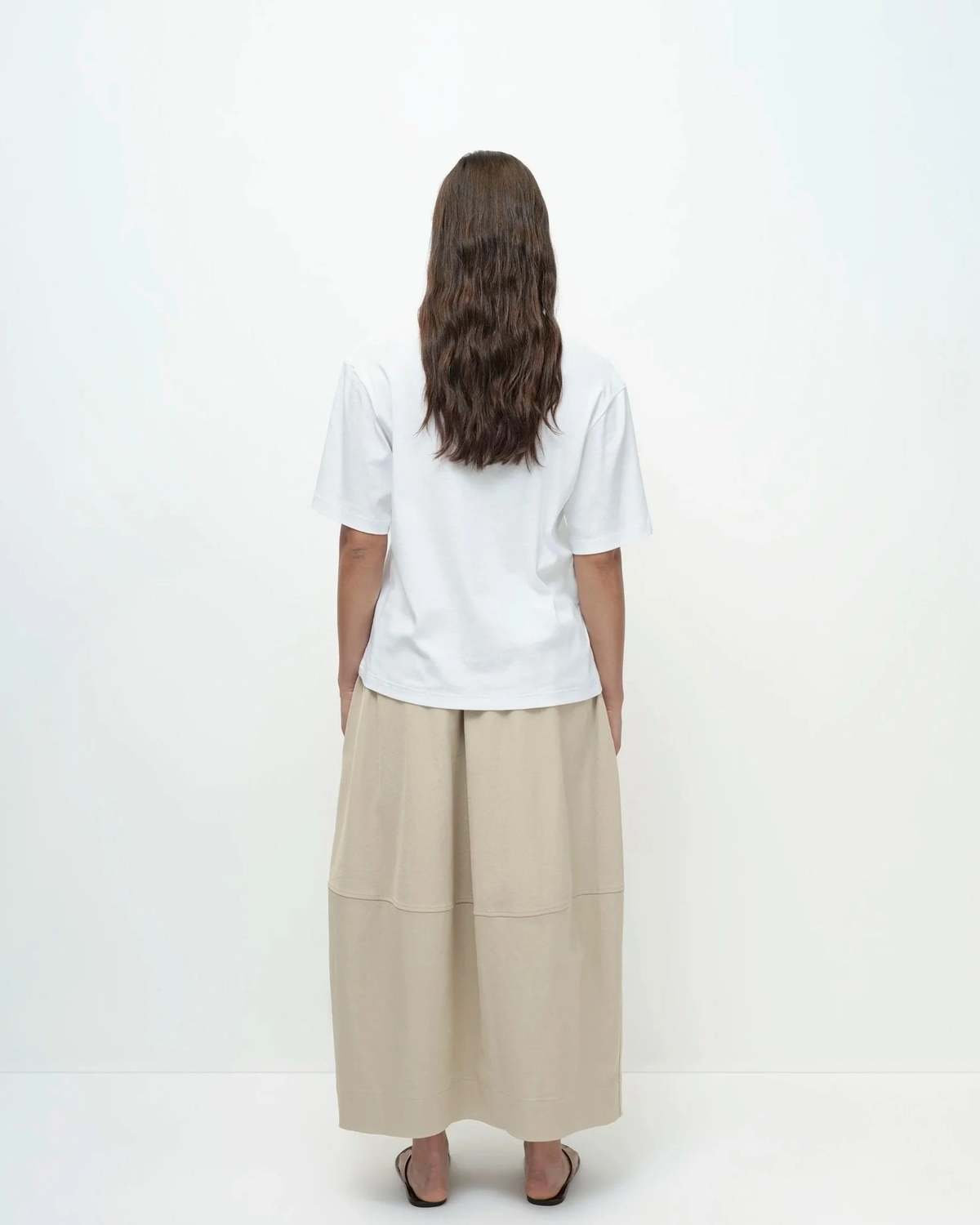Woman wearing a white shirt and beige skirt on a white background