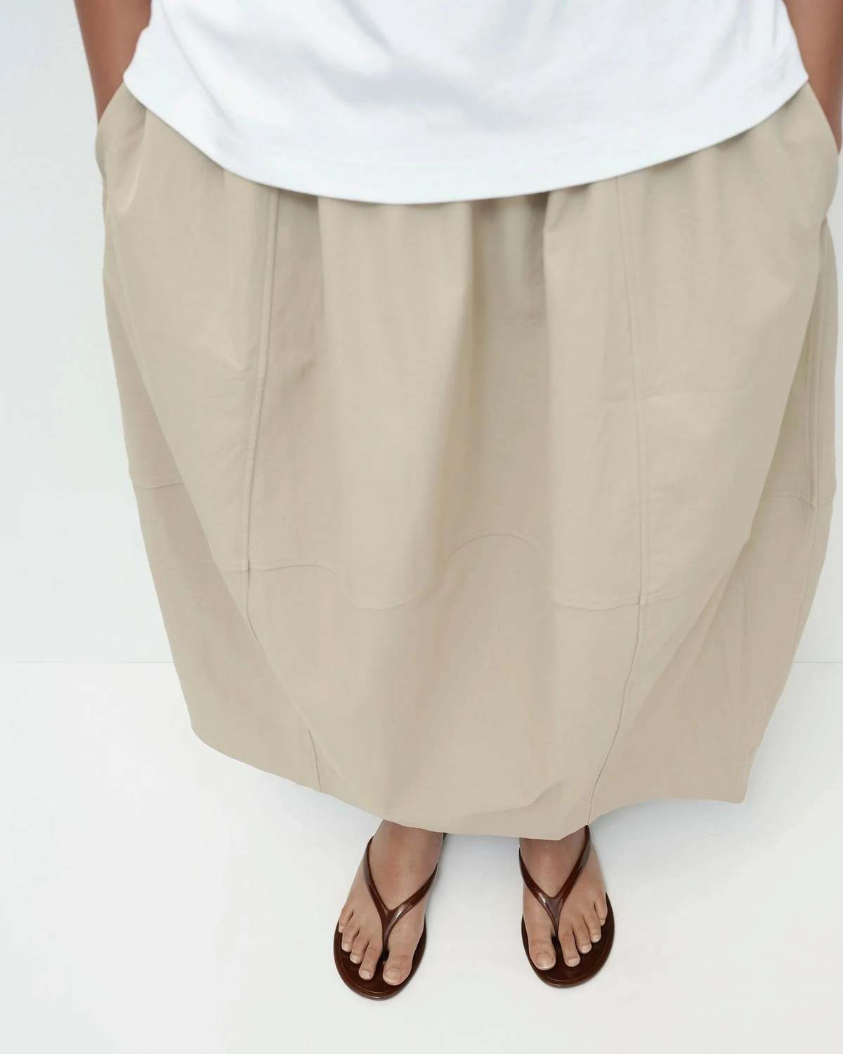 Person wearing a white top and beige wide-leg pants on a white background