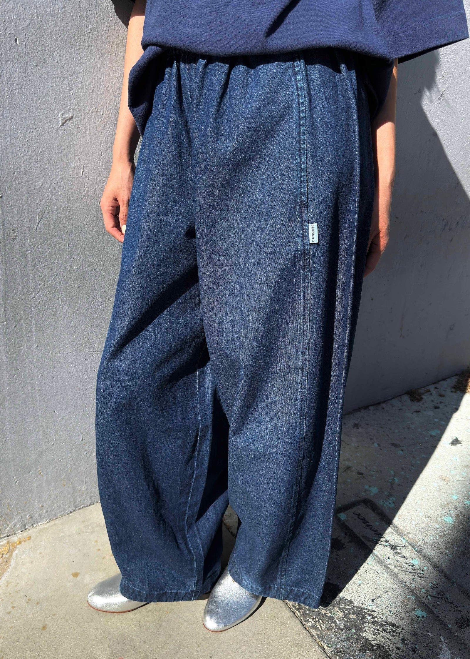 Person wearing blue wide-leg jeans against a gray wall.