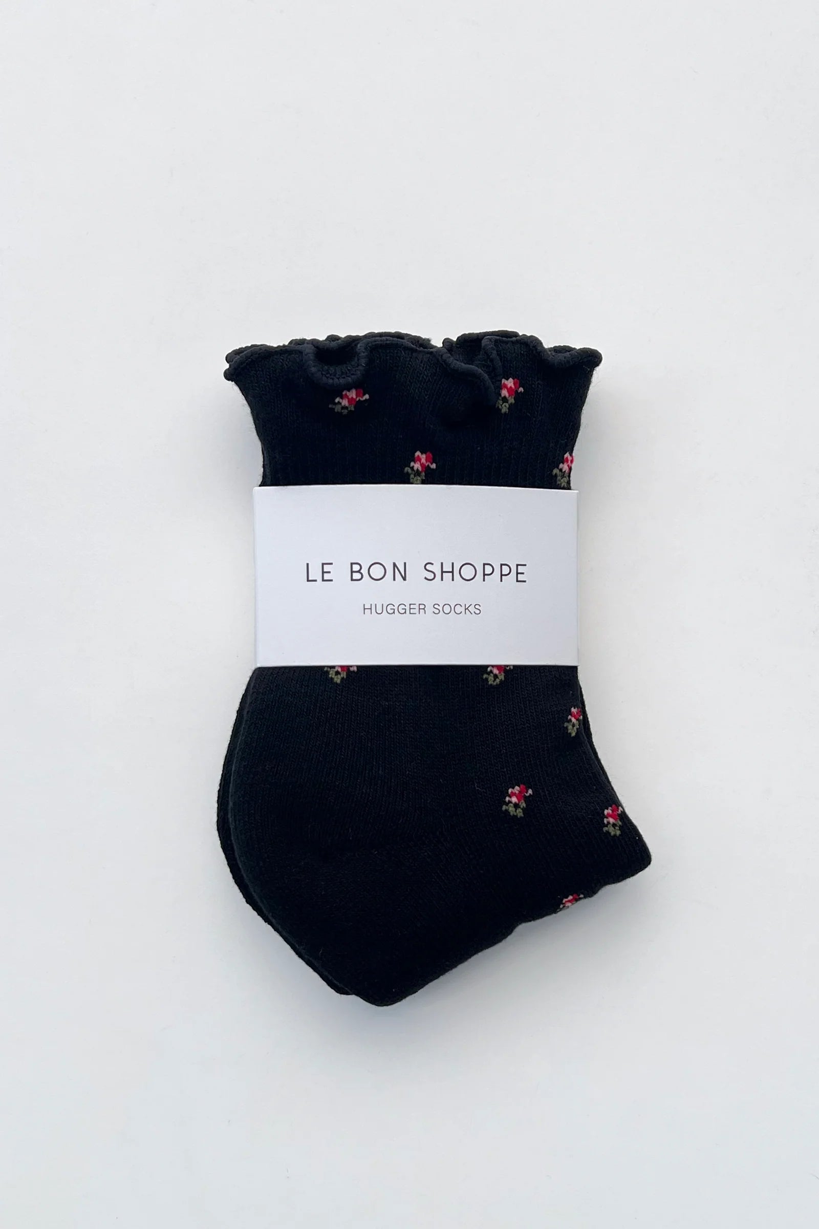 Pair of black socks with small floral pattern on a white background, branded 'Le Bon Shoppe'.