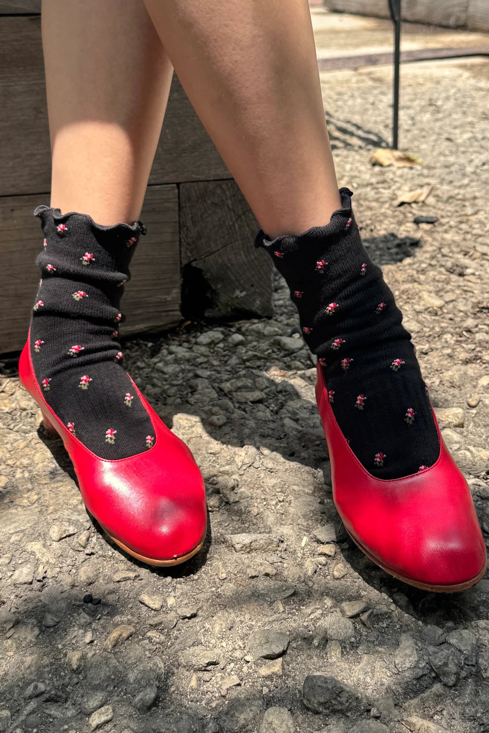 Red shoes with black socks worn on a street.