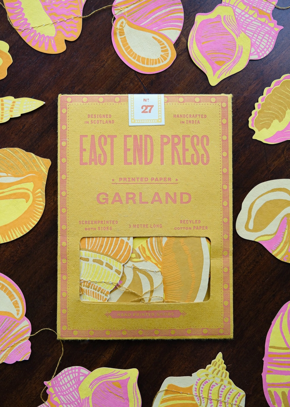 Packaged Garland by East End Press with decorative paper shapes on a wooden surface