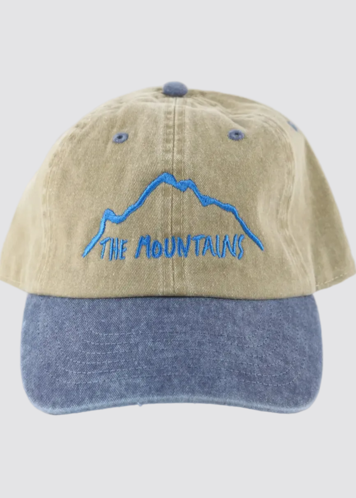 Two-tone cap with blue mountain design and 'The Mountains' text on a white background