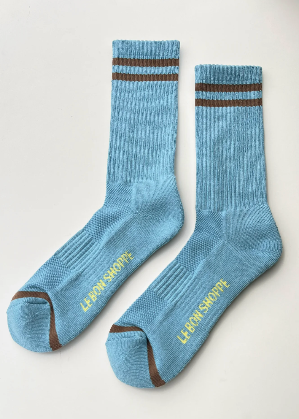 Pair of blue socks with brown accents and 'Le Monde Shoppe' branding on a light gray background