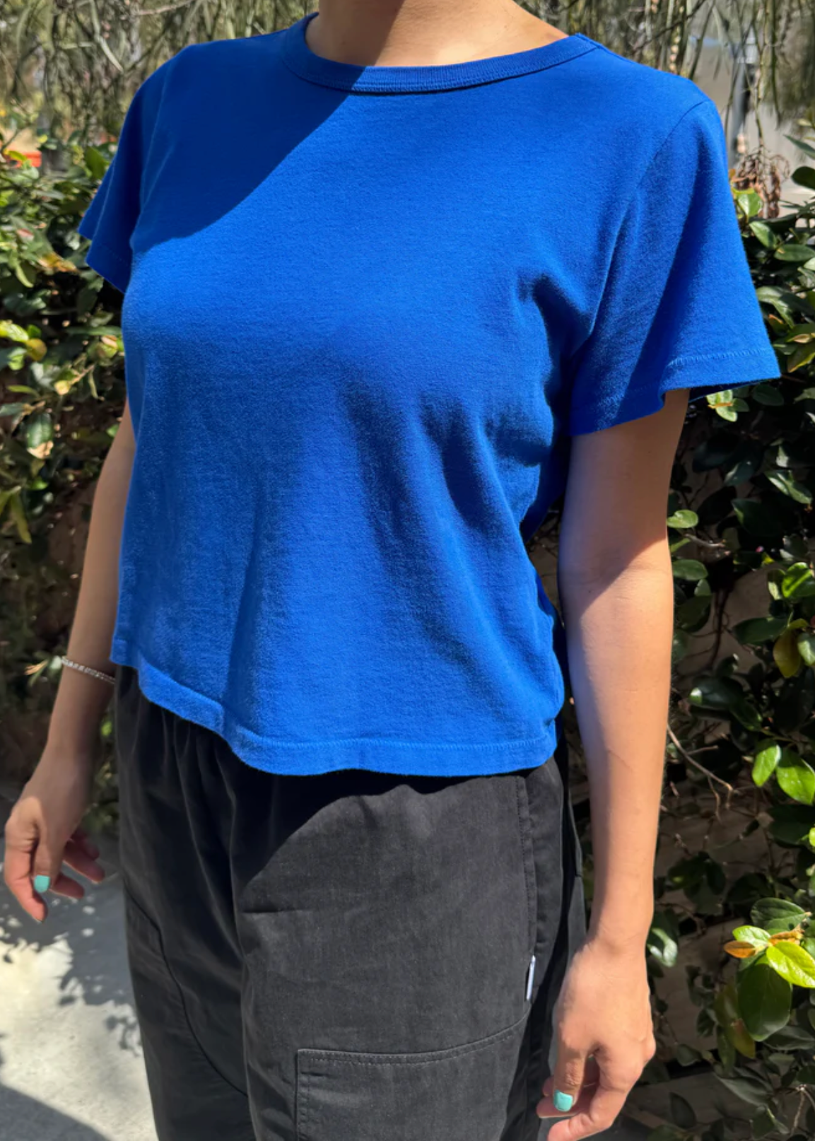 Person wearing a blue t-shirt and black pants outdoors