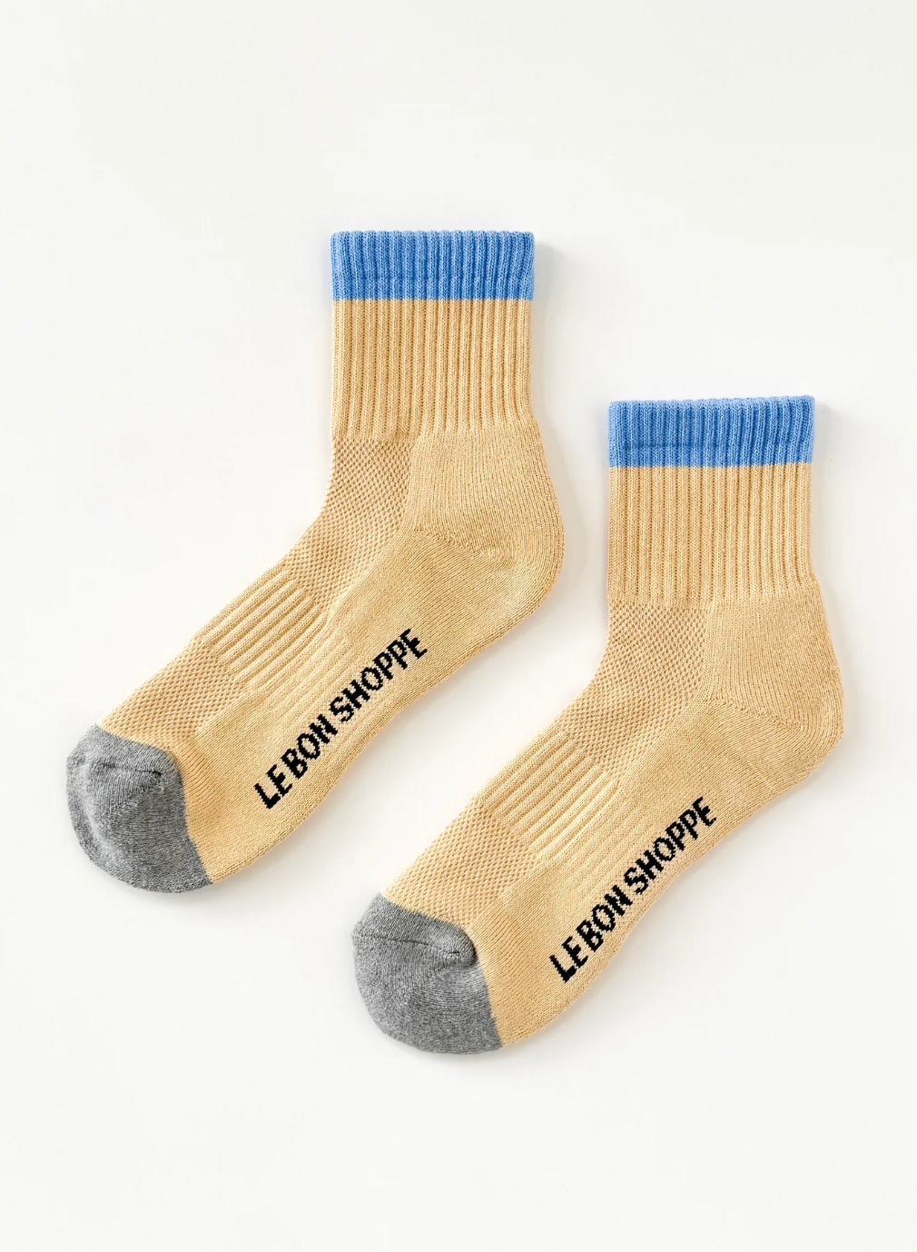 Pair of beige socks with blue tops and gray toes on a white background, featuring 'Le Bon Shoppe' branding.