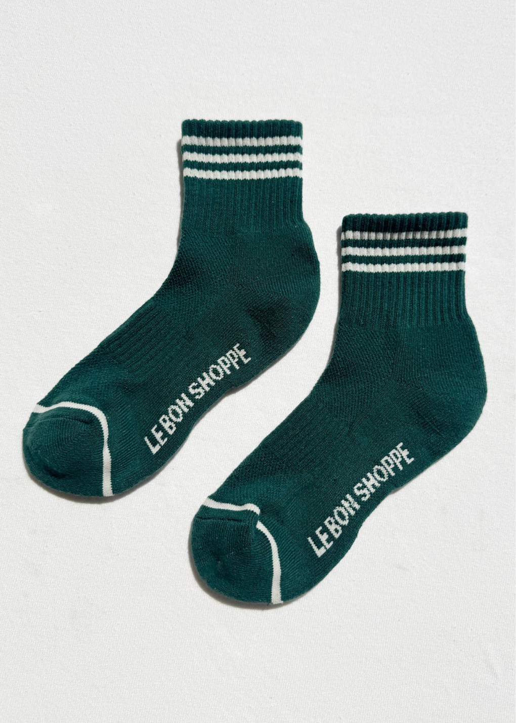 Two green socks with white stripes and 'LEBON SHOPPE' branding on a light gray background.