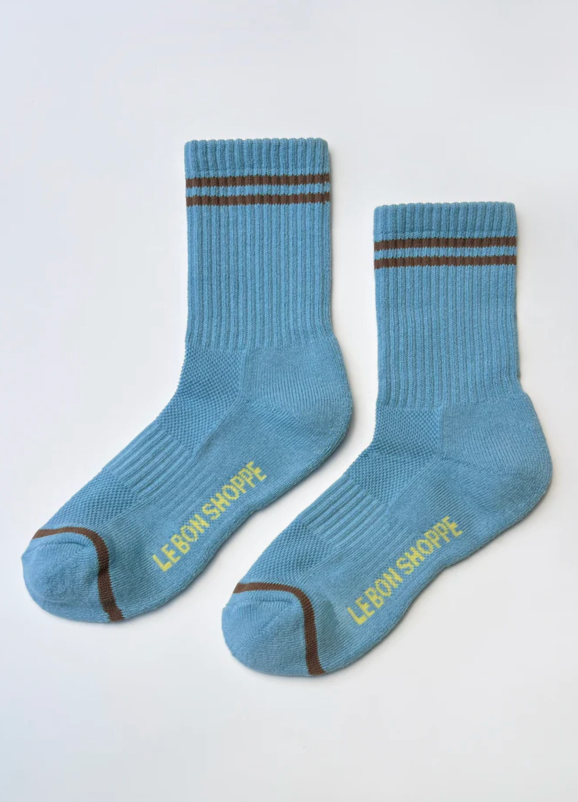 Pair of blue socks with brown accents and 'Le Bon Shoppe' branding on a white background