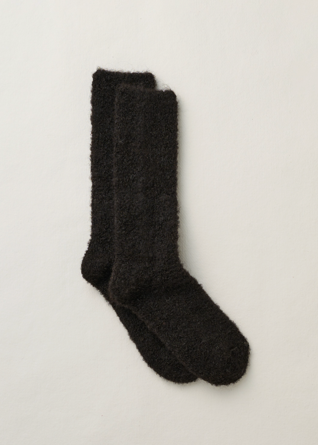 A pair of black fuzzy, textured socks laid flat on a clean, off-white background.