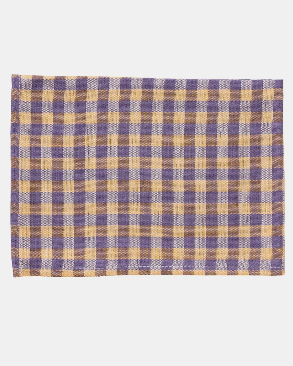 A rectangular woven  cloth with a classic gingham check pattern in purple and tan, laid flat against a light gray background.