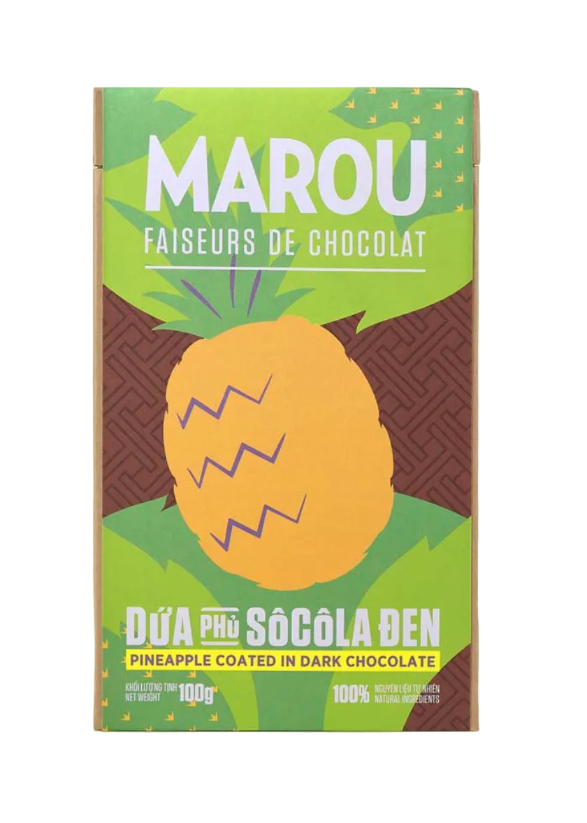 A box of Marou chocolate-coated pineapple candy on a light beige background. The packaging features a bright green top section with the brand name 'MAROU' in white, a large yellow pineapple illustration in the center, and a dark brown chocolate-textured lower section with green leaves at the top and the flavor text 'PINEAPPLE COATED IN DARK CHOCOLATE' at the bottom.