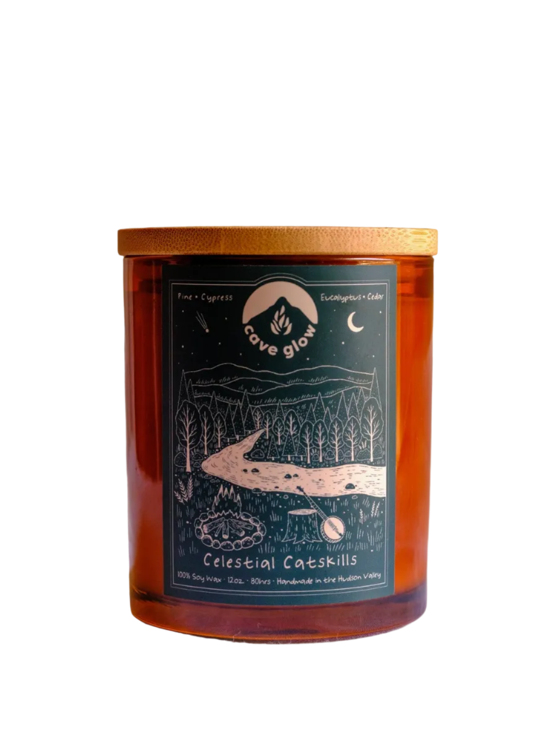 amber glass candle with wooden topper and green label with Cave Glow branding, info and drawing of the "celestial catskills," landscape with trees, fire, moon, mountains and more.