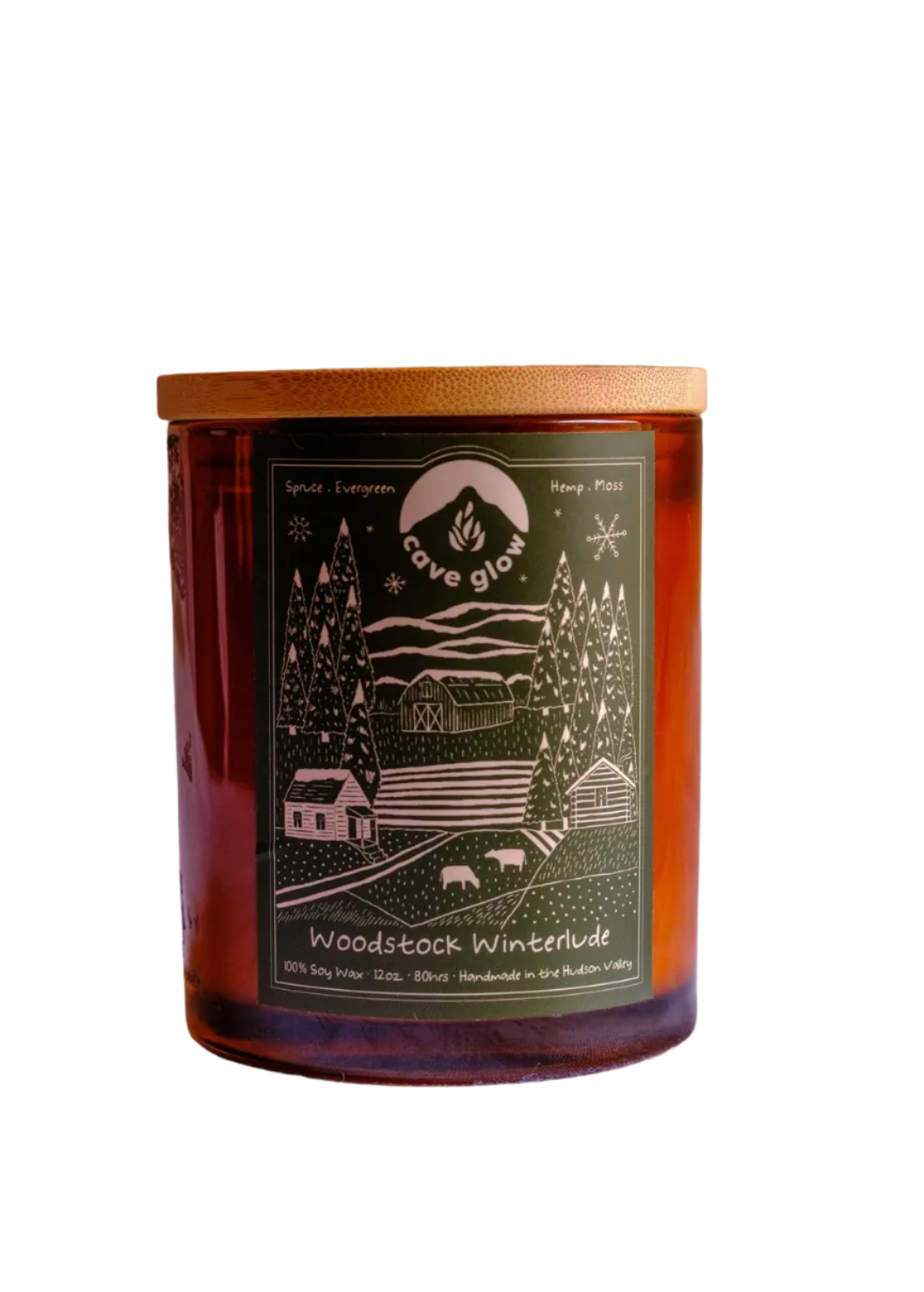 amber candle with wooden top, dark green label with branding and illustration of snowy outdoor landscape/farm with animals trees, a barn, a house, mountains and more